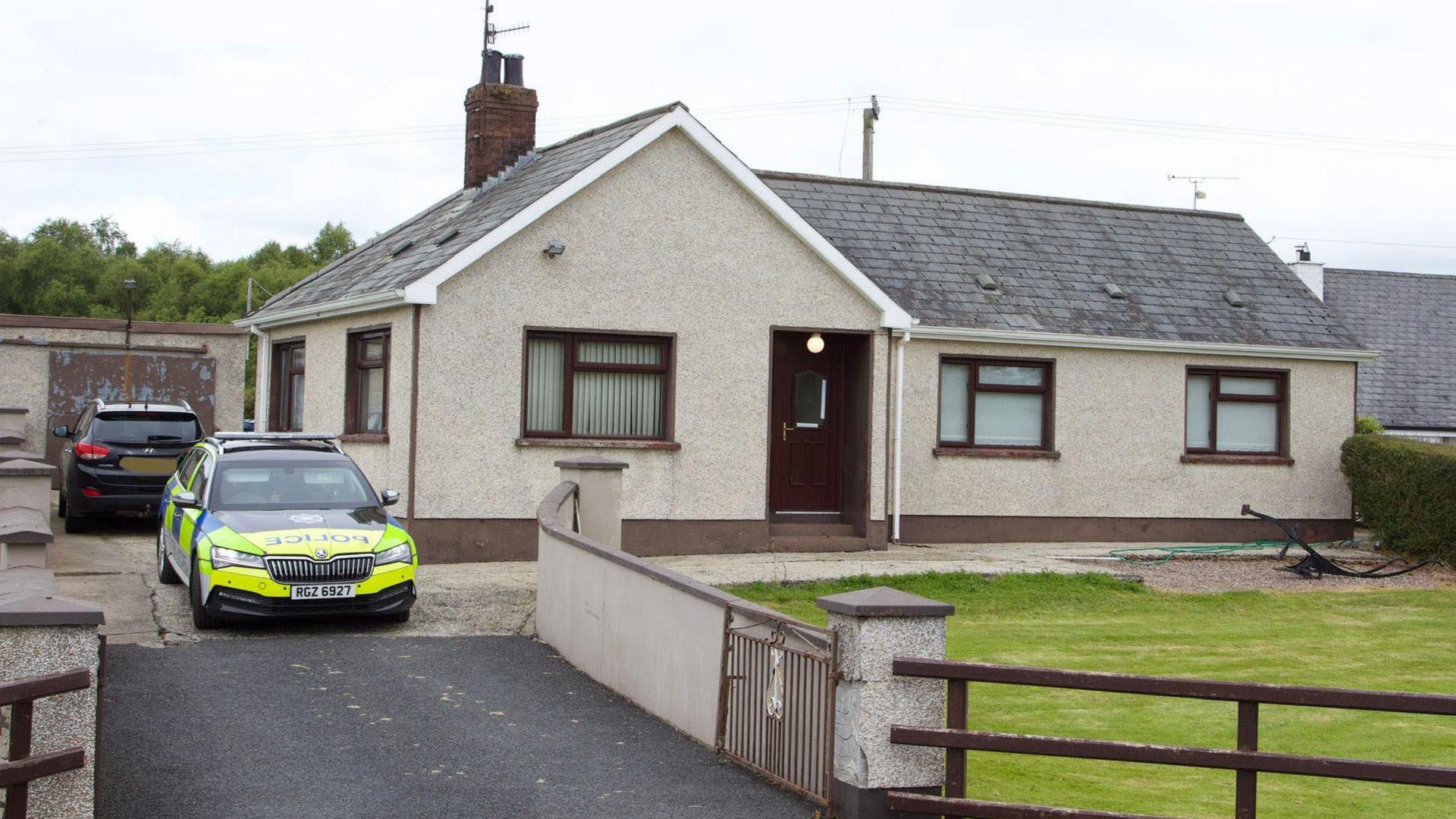 Michael McConville's home on Annaghmare Road in Crossmaglen in June 2024.   There is a police car parked outside the detached bungalow and there is another black vehicle parked in the driveway.