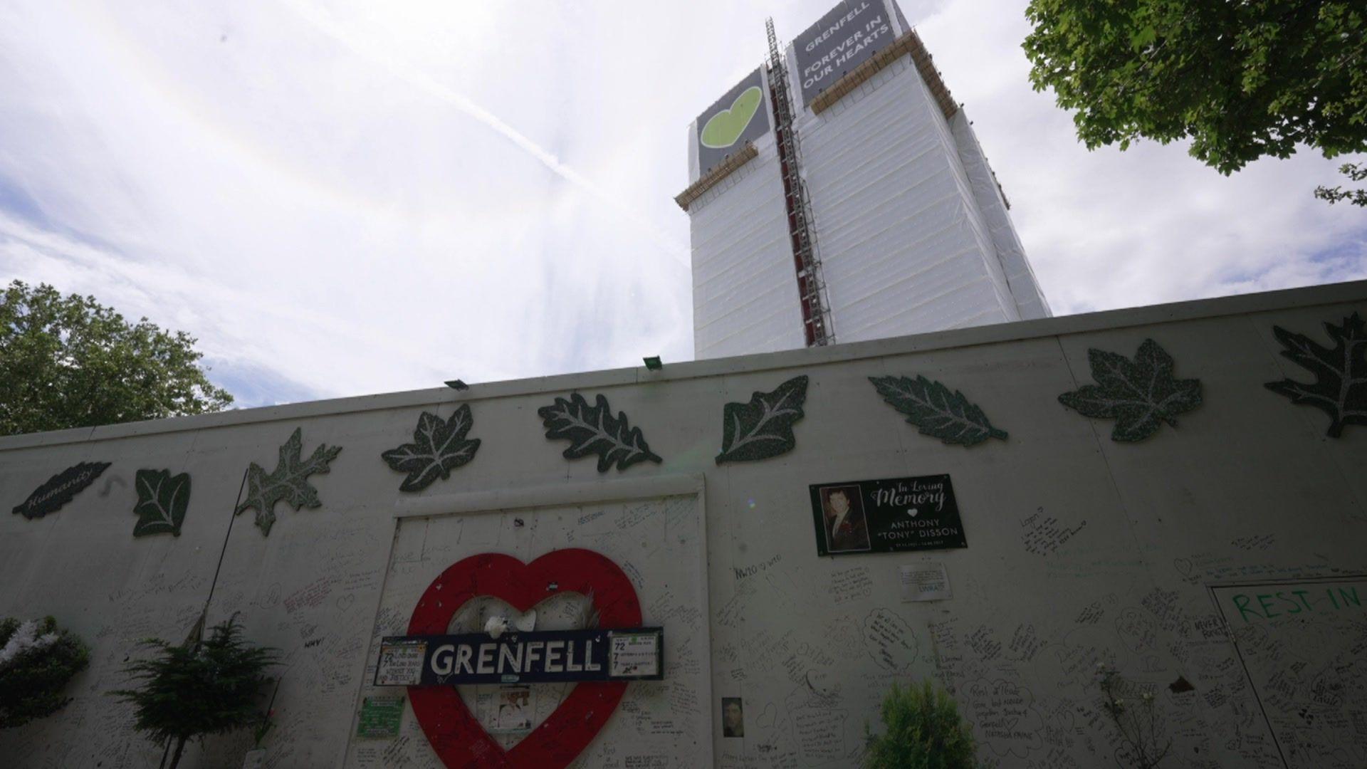 A Greenfell sign inside a red heart shape on white boarding in front of Grenfell Tower