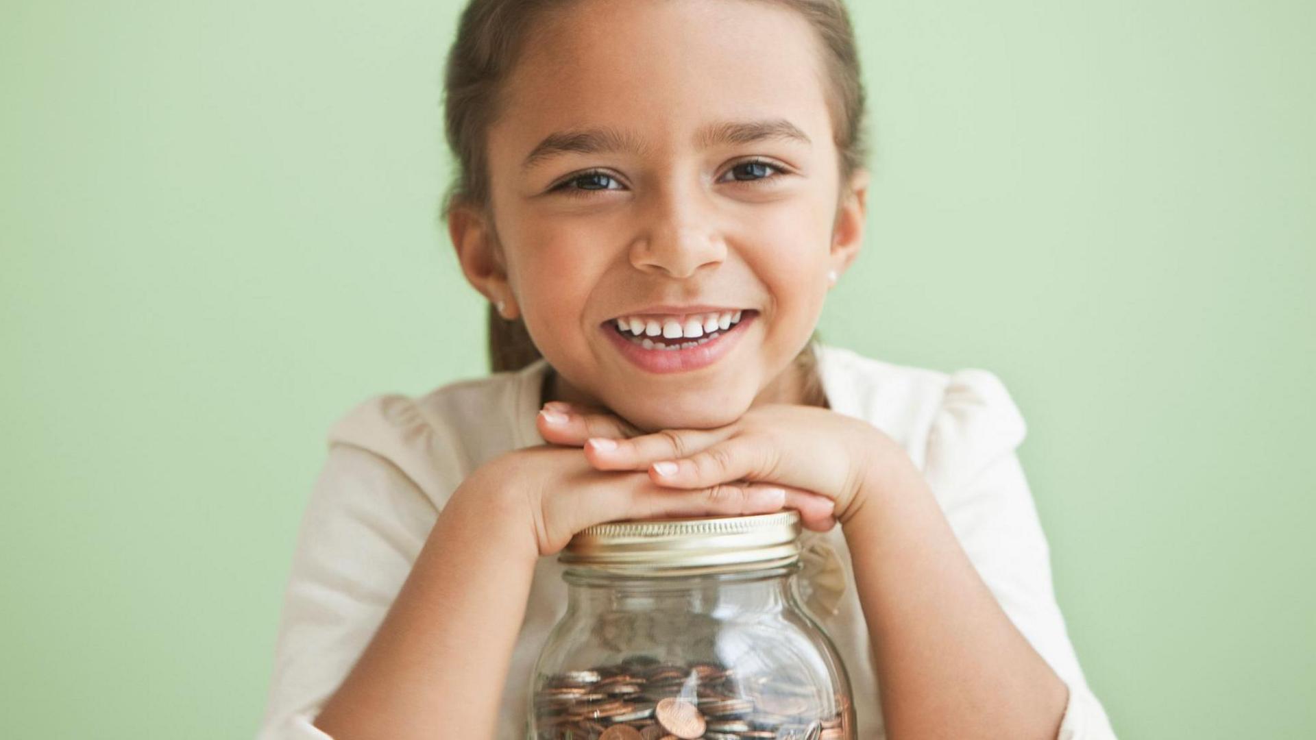smiling girl with jar of coins. 