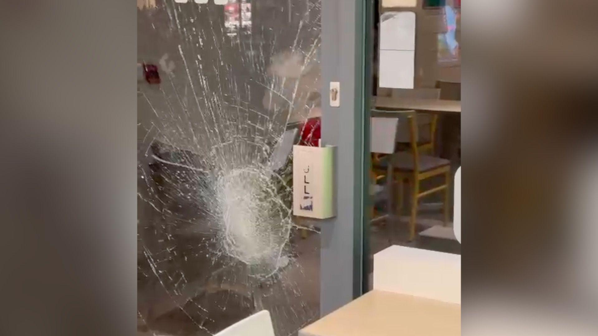A smashed window in the door of Subway