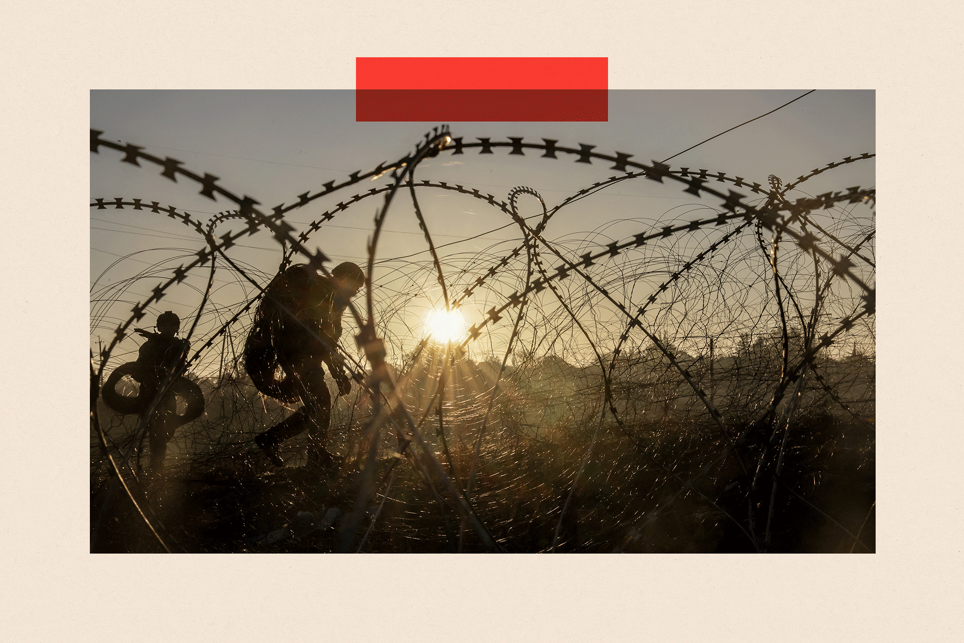 Soldiers walking alongside barbed wire as the sun sets