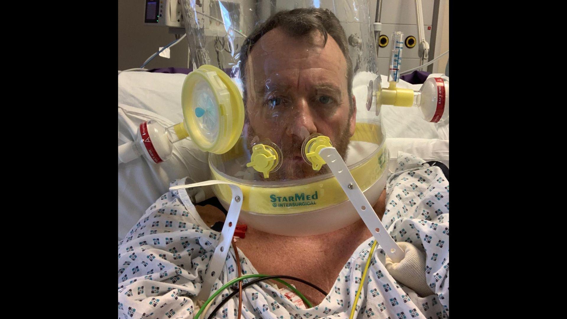 Laurence Penn, wearing hospital clothing, has a breathing apparatus around his head in Worthing Hospital.