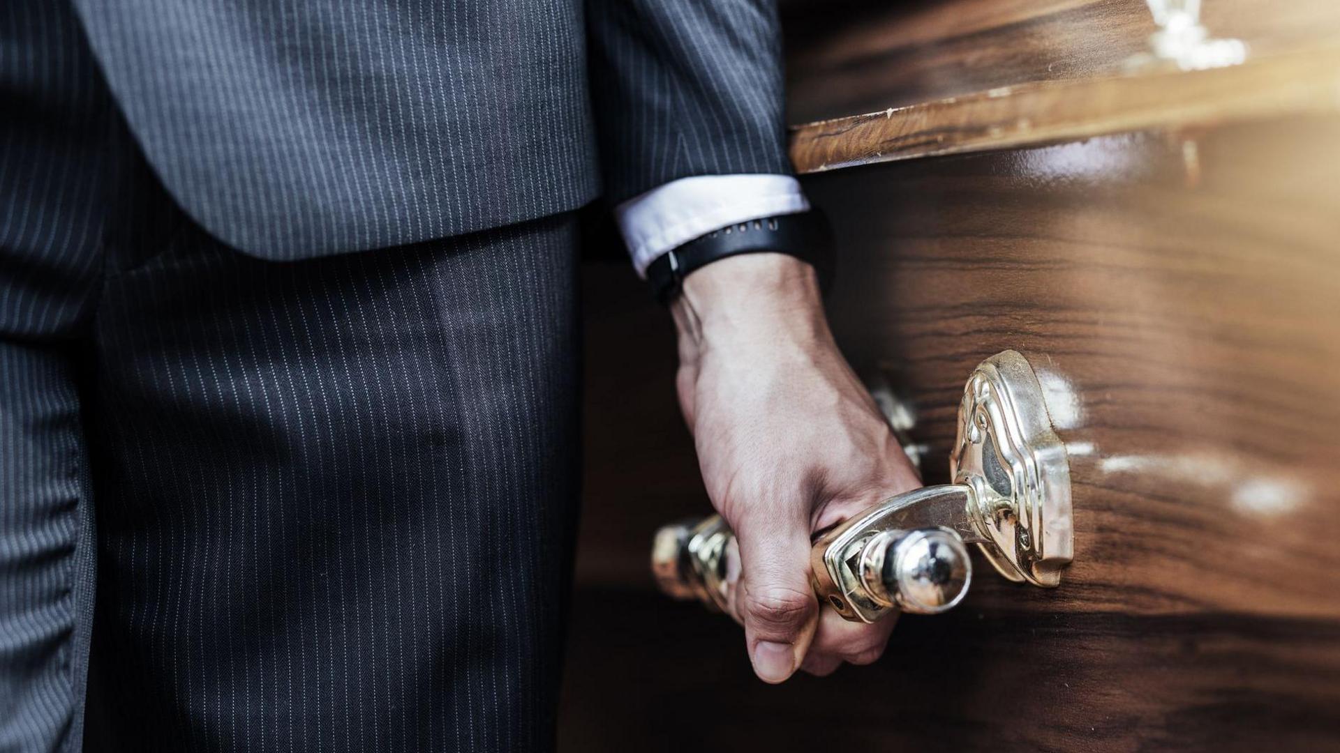 Close up of a man's hand carrying a coffin