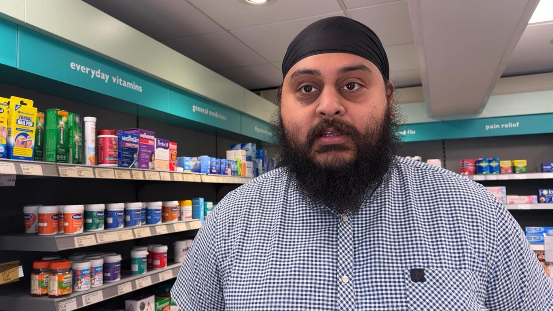 Pharmacist Manpreet Gill in front of shelves in the store