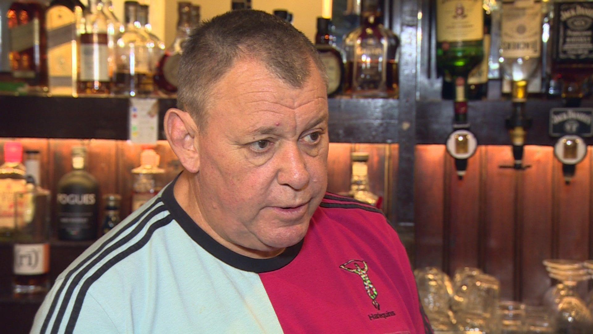 Craig Douglas wearing a Harlequins rugby top in a pub with bottles of spirits behind him