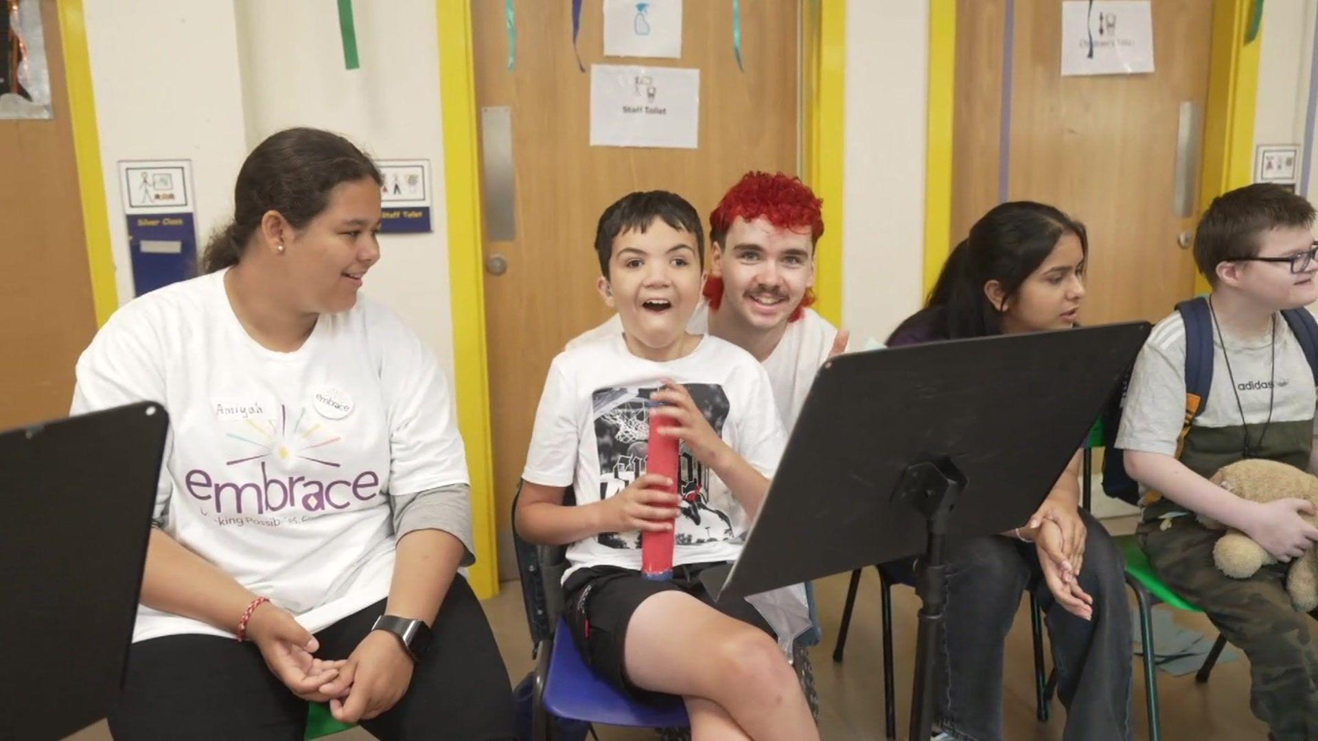 A group of children sitting behind music stands, taking part in activities at Embrace