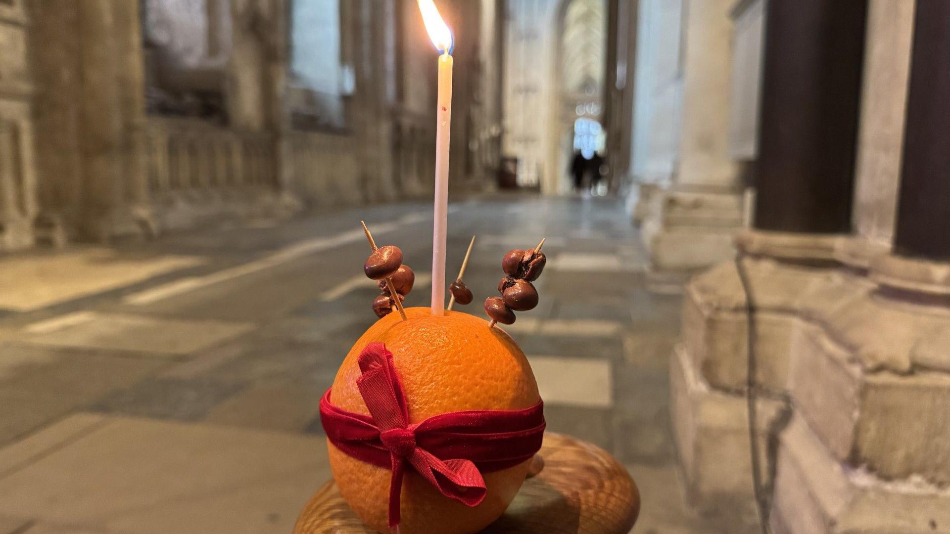 An orange with a candle poking out the top in a cathedral