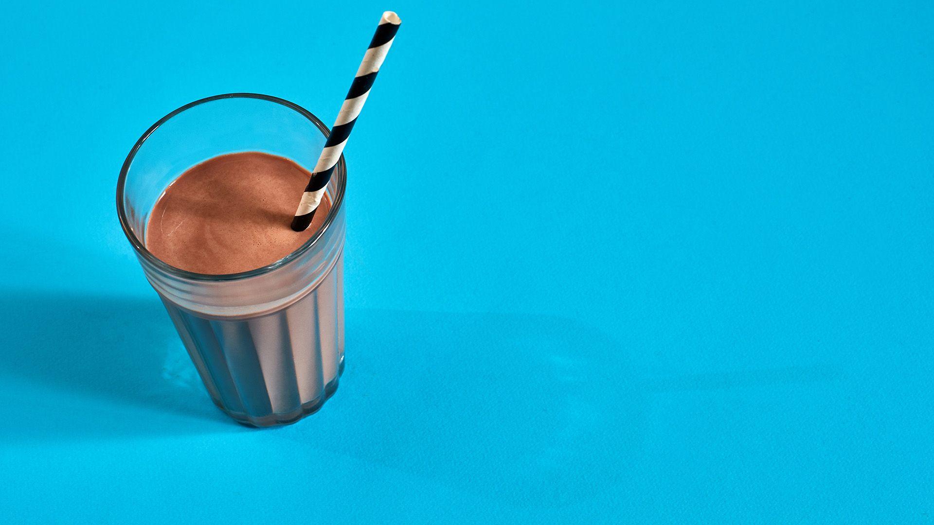 Glass of chocolate milk on blue background