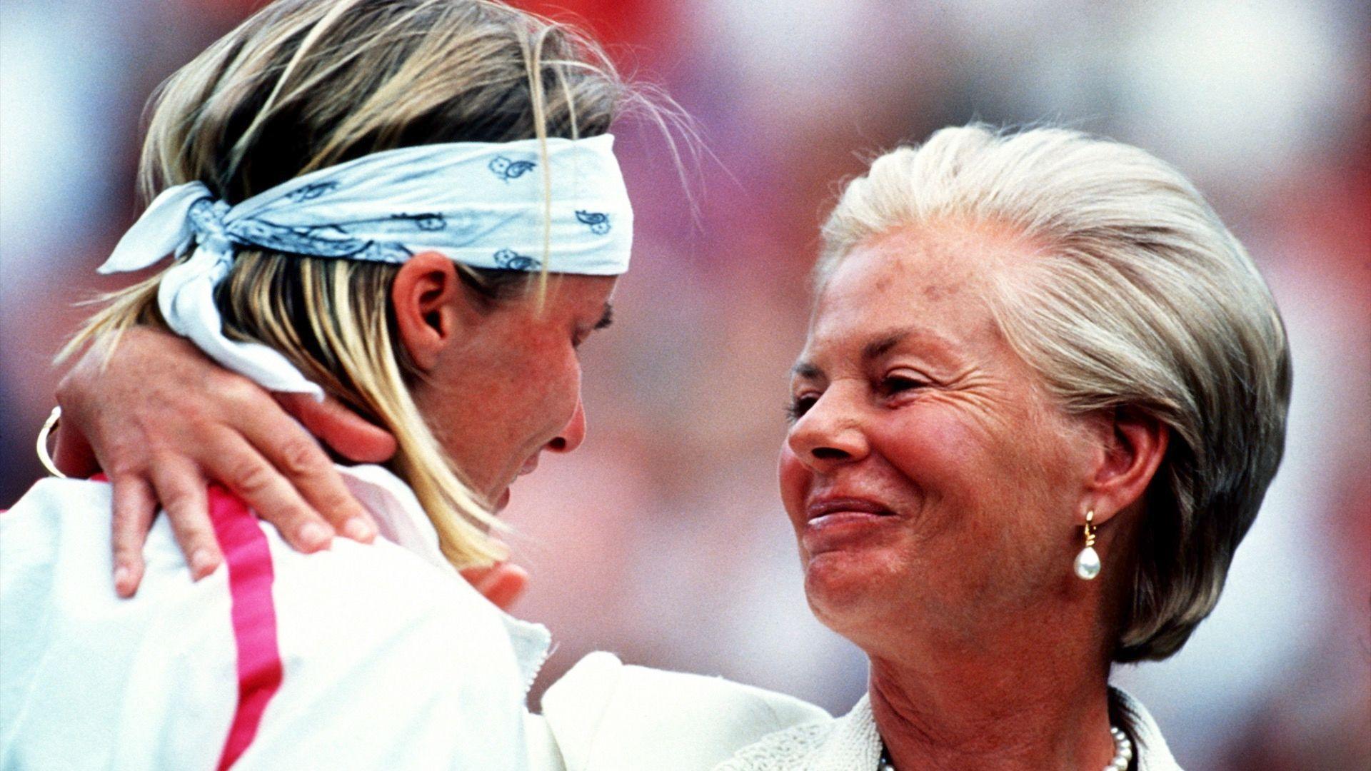 The smiling duchess dressed in white has an arm around Novotna, who is wearing a tracksuit top and headband.