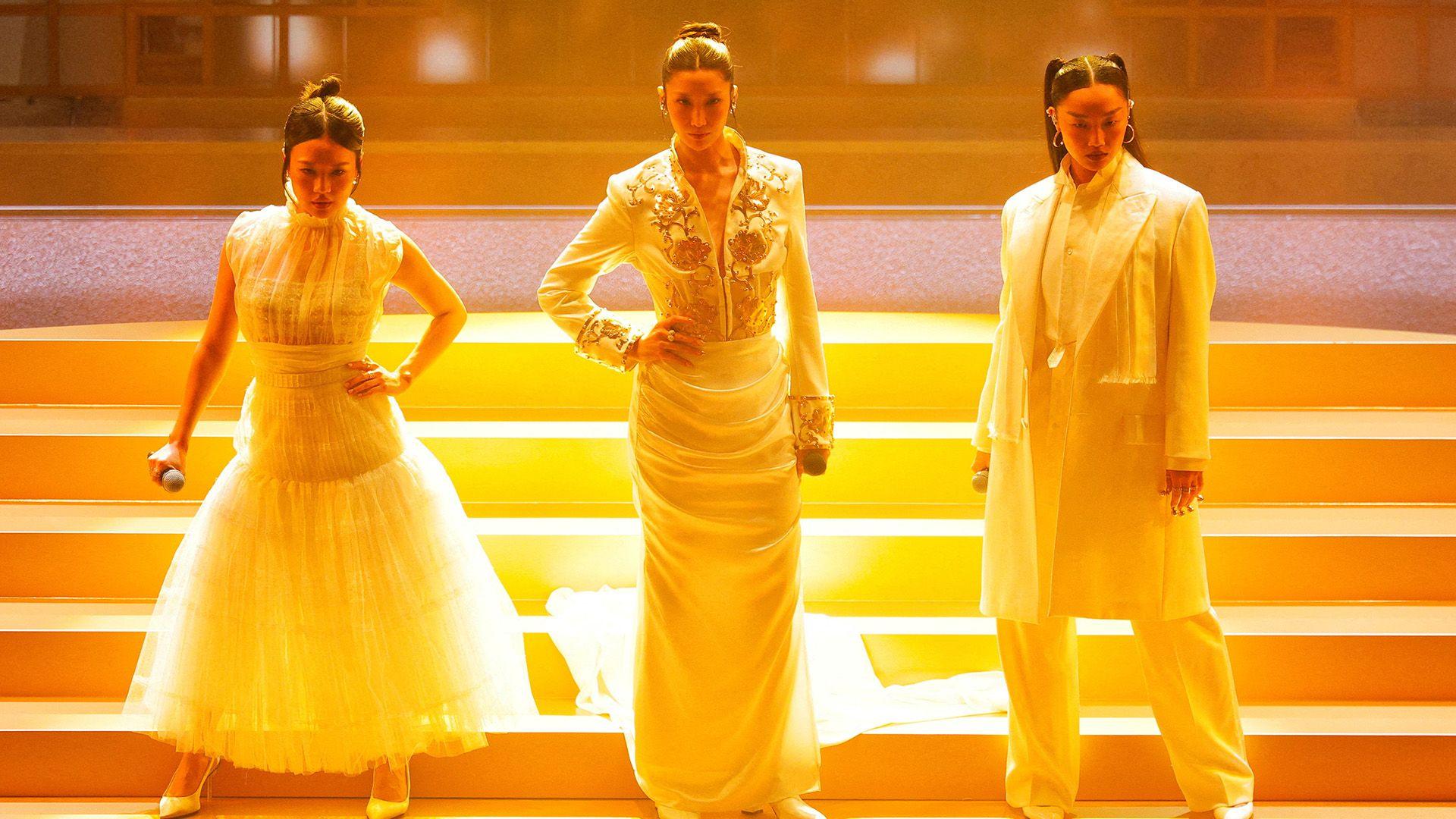 Rei Ami, EJAE, and Audrey Nuna from KPop Demon Hunters perform on stage during the Oscars show at the 98th Academy Awards in Hollywood. They are lit up in a golden light on the stage as they pose before they sing