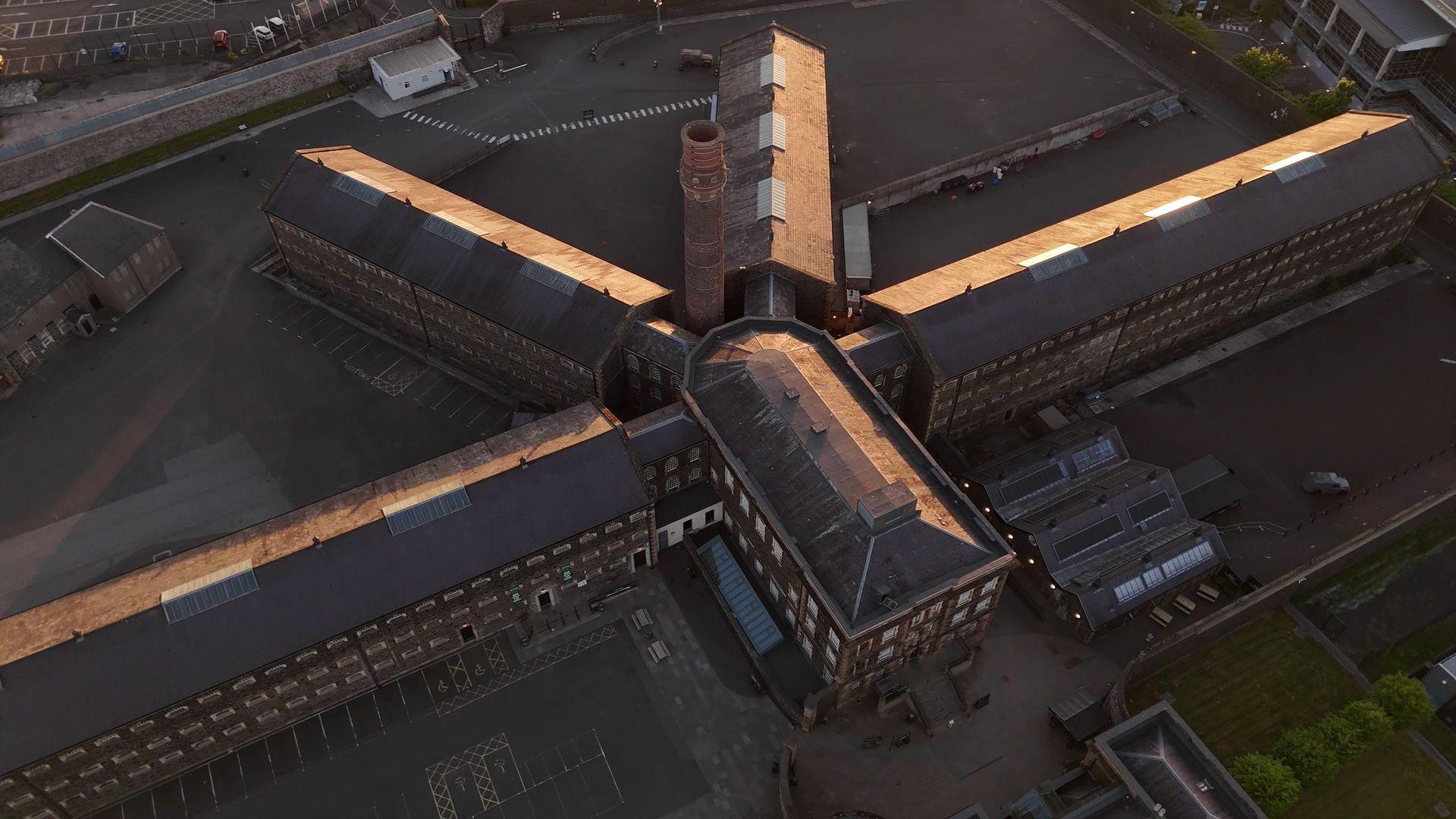 An aerial drone image of the former Crumlin Road jail which consists of a large central block with four long wings radiating from it. 