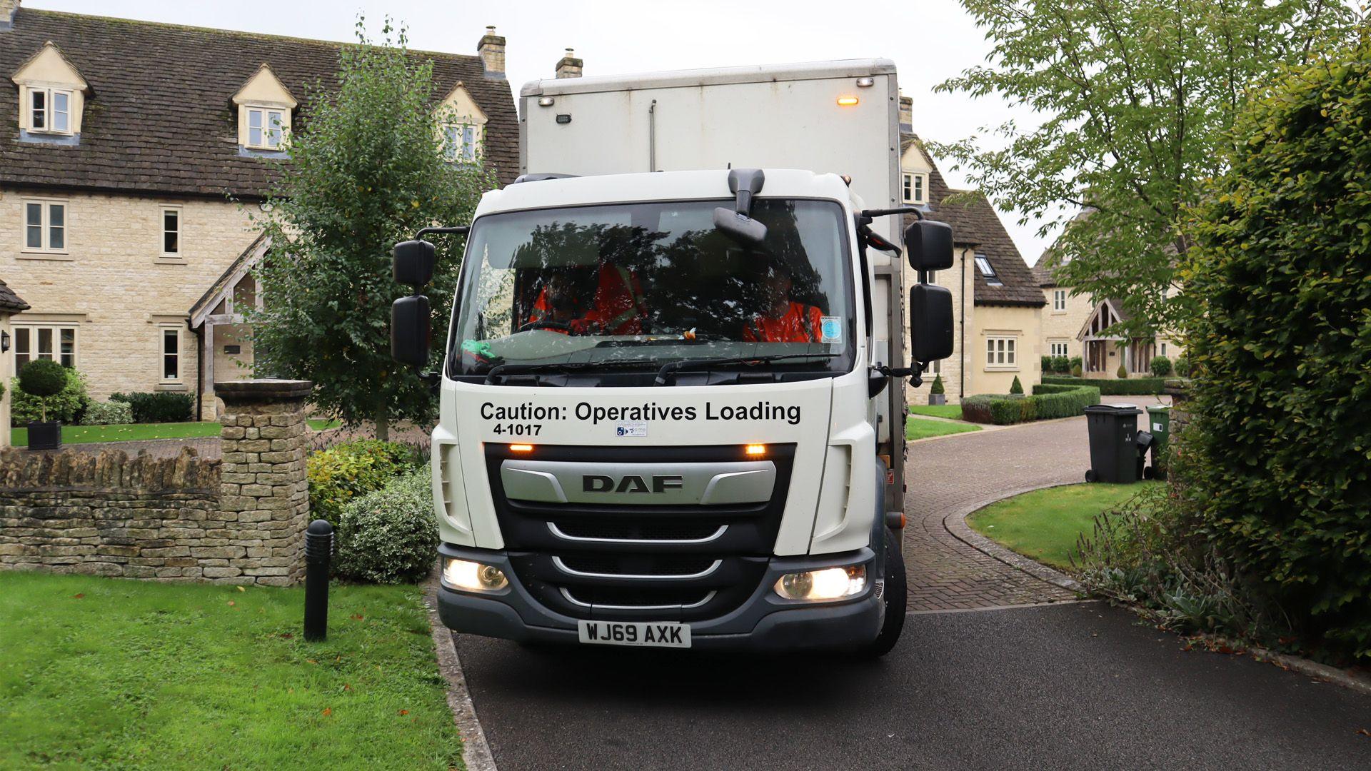 A refuse truck driving out from the entrance of a close