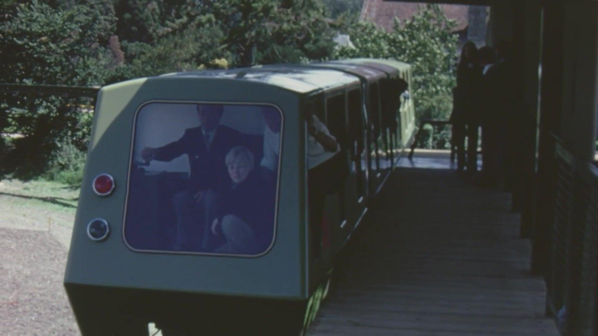 A picture from 1974 of the monorail system. It is a green train, and the front cab is full of people.