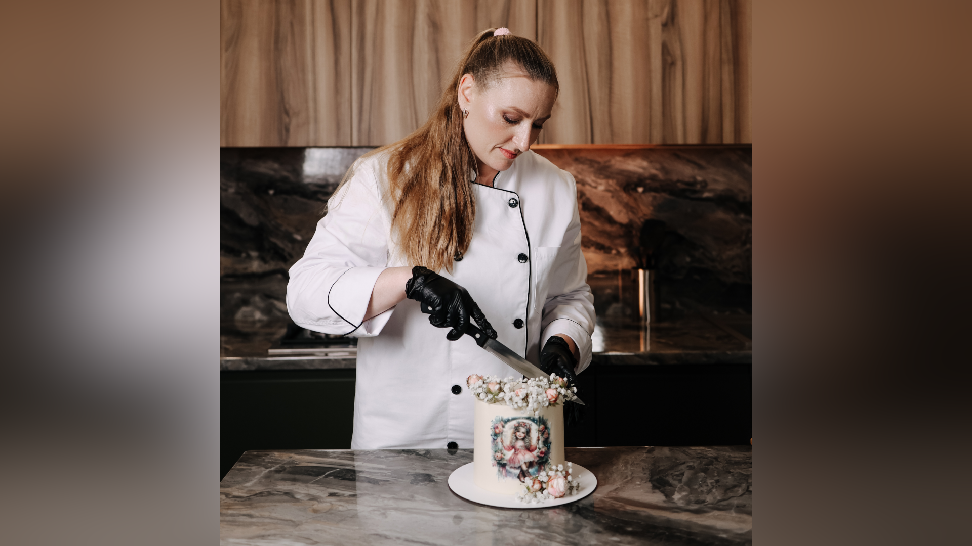 Mrs Hoian is pictured cutting a small white cake. She wears a white chef's apron and black gloves.