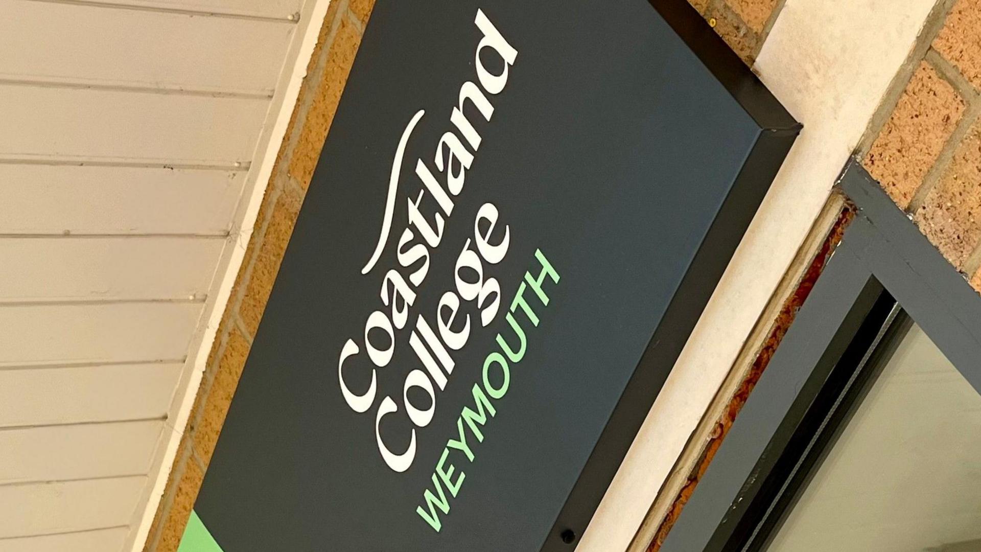 The new sign above the door at Weymouth campus. Coastland College Weymouth is written over three lines in white and pale green on a black background with a wavy white line at the top.