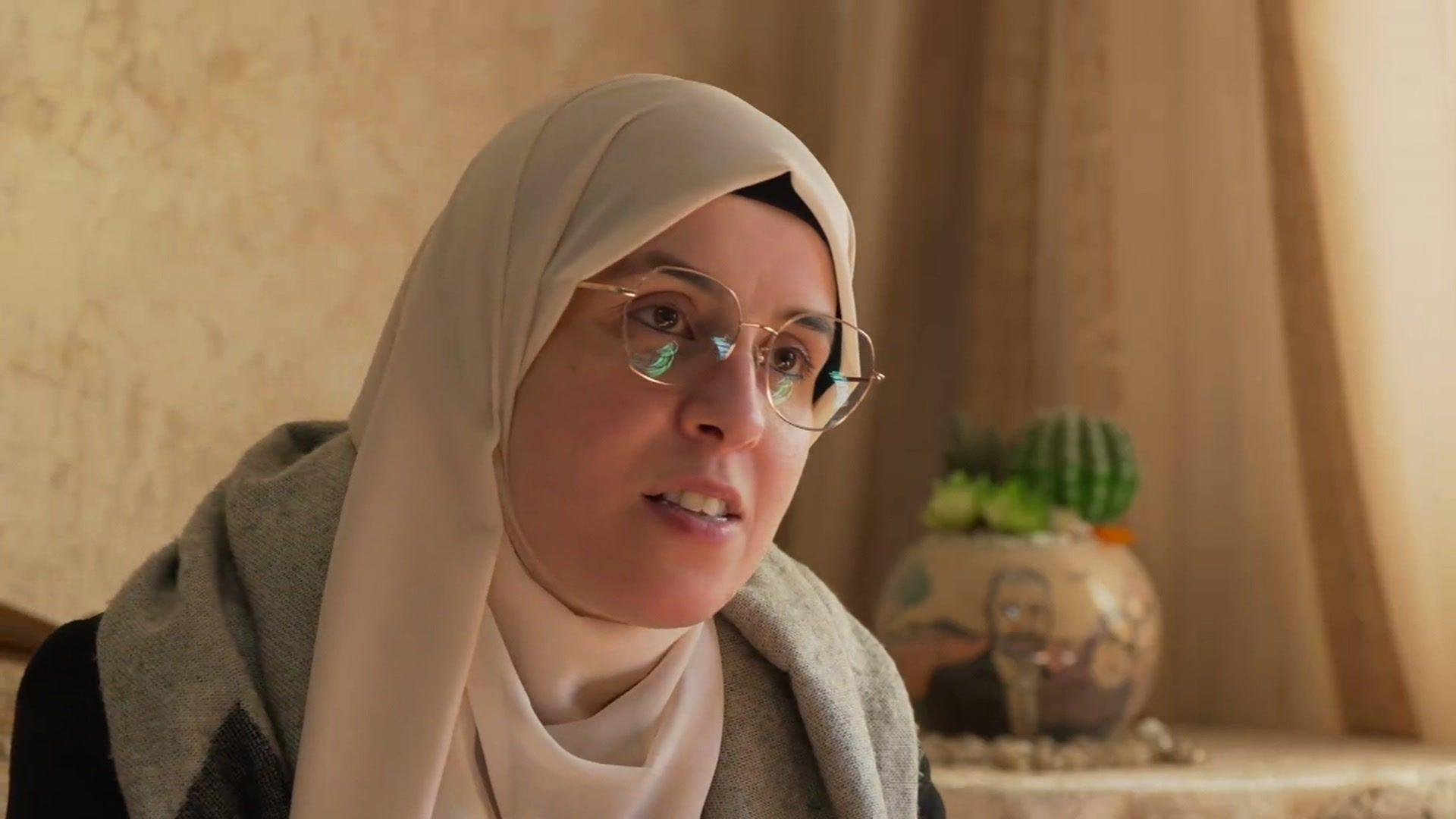 Palestinian journalist Bushra al-Tawil wearing a cream headscarf and glasses at her family's apartment in Ramallah