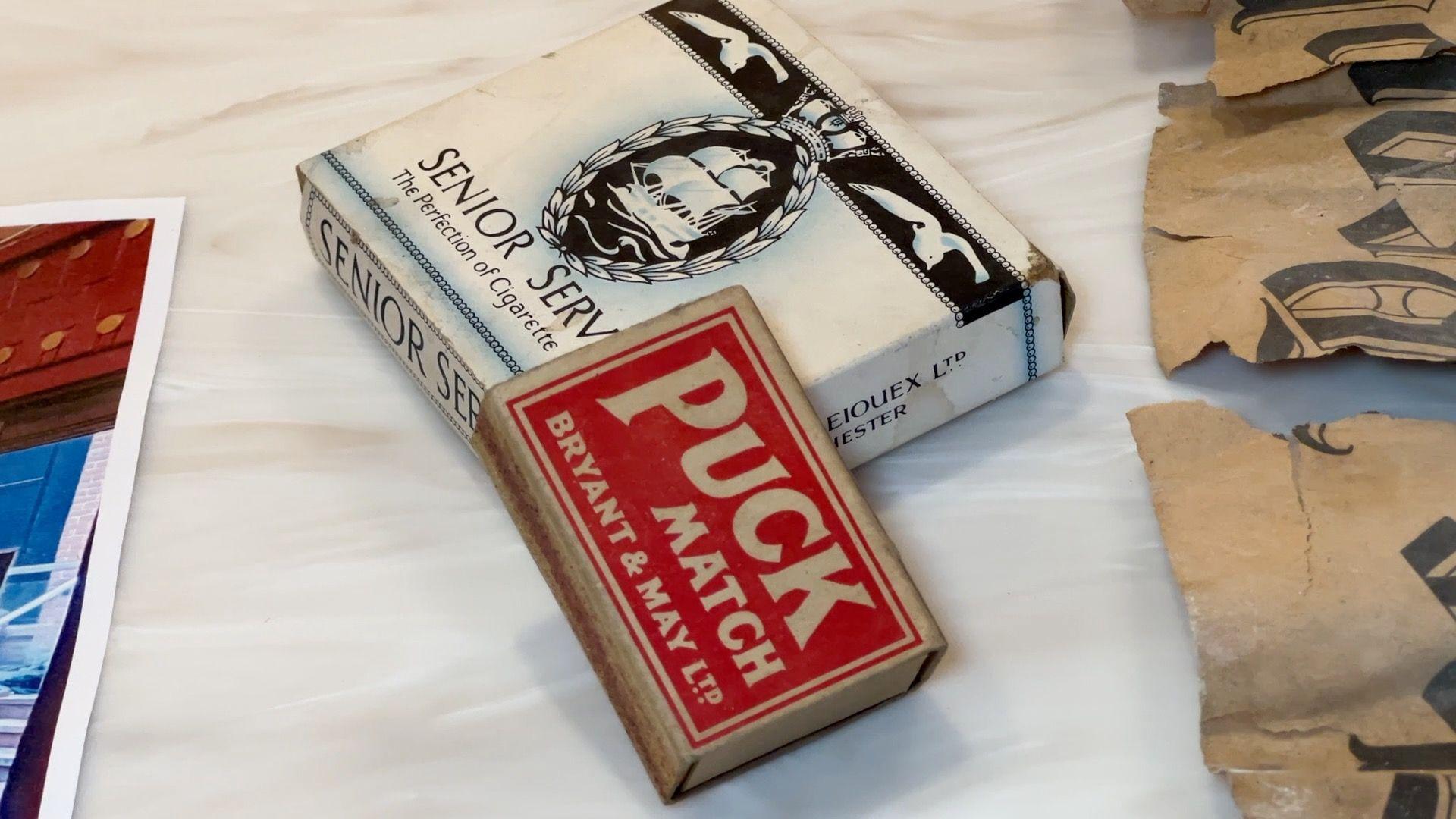 A black and white box of cigarettes with a red box of matches.