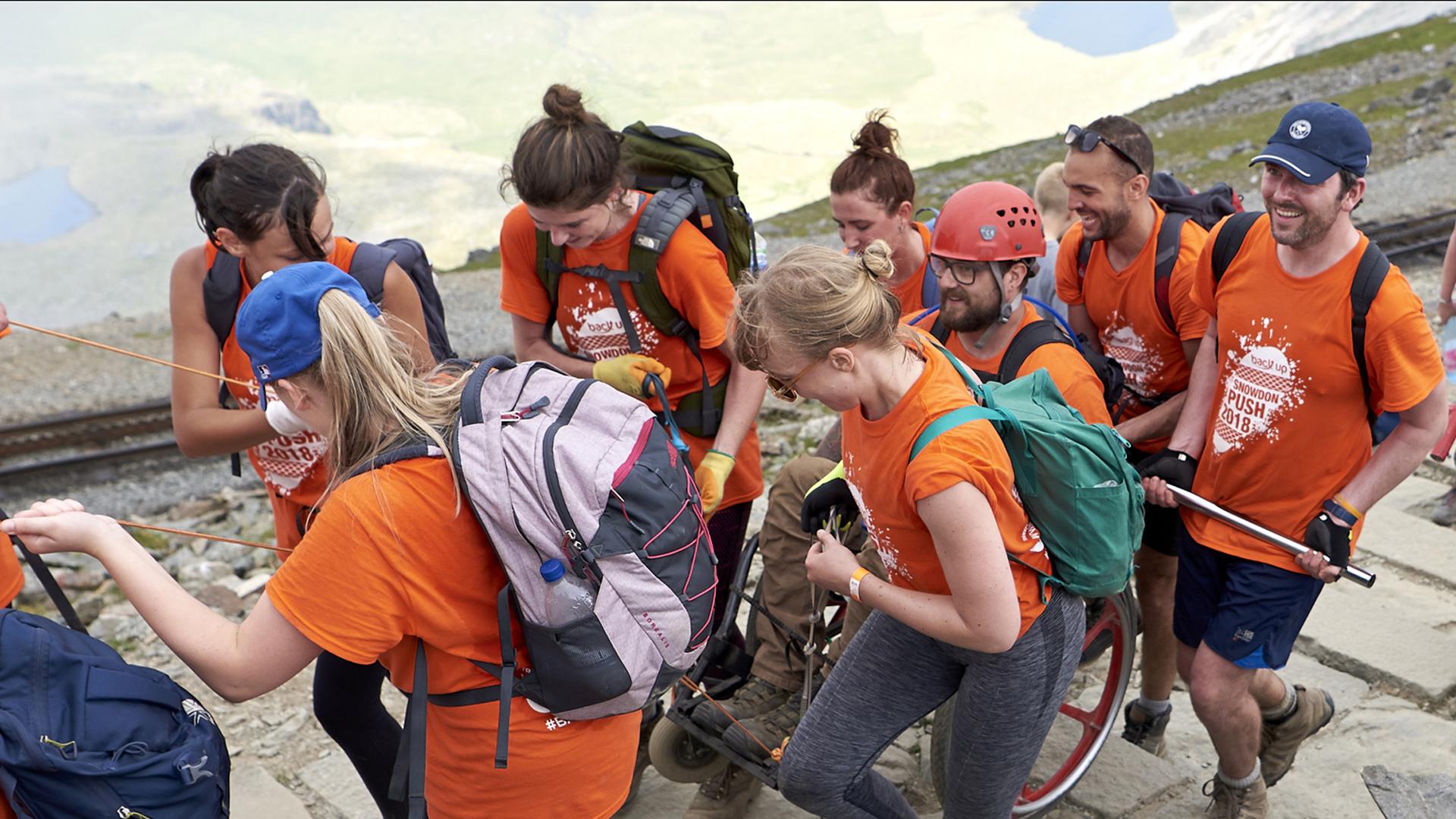 Team pushing wheelchair user up Snowdon