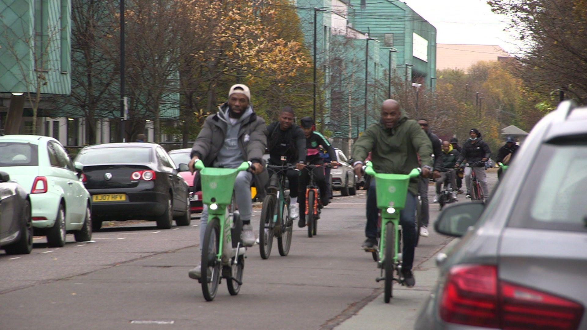 A group of fathers riding bikes on the road towards the camera 