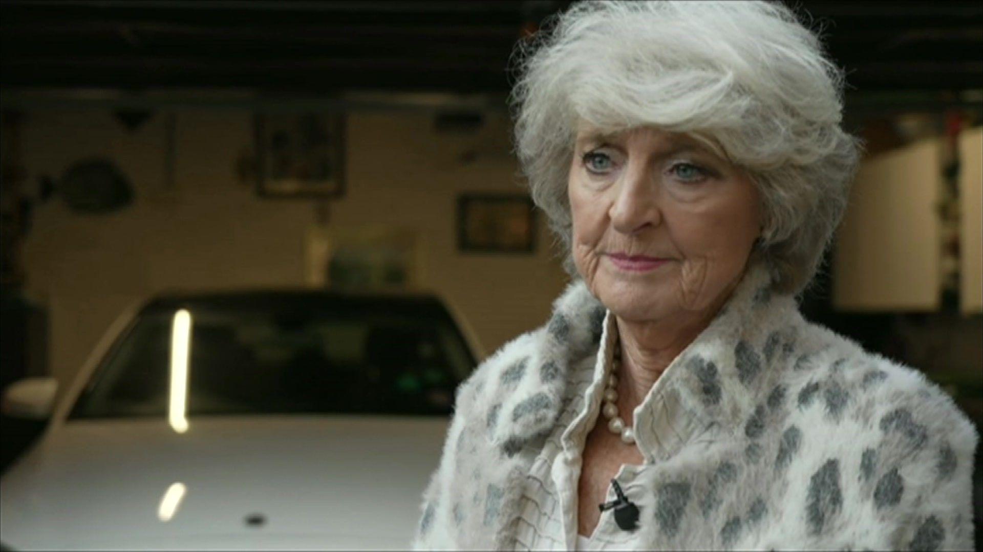 Stella Roscoe standing in front of a white car on her driveway.