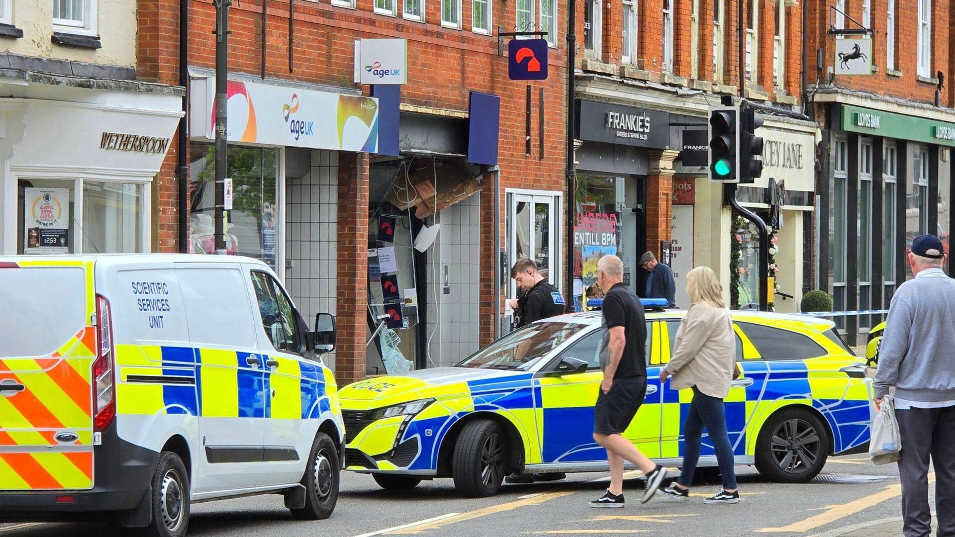 Police cars outside the Nationwide building society with its front smashed in by ram-raiders