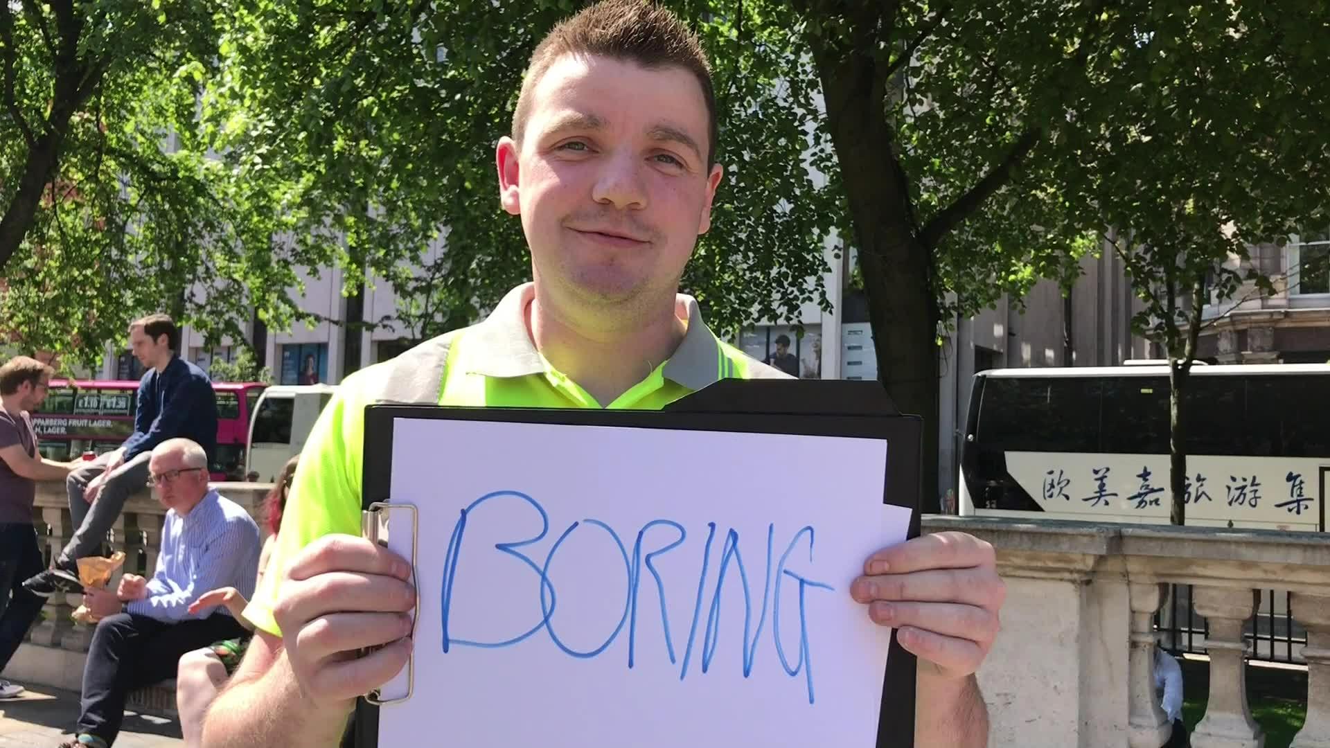 A man holding a sign that reads: Boring