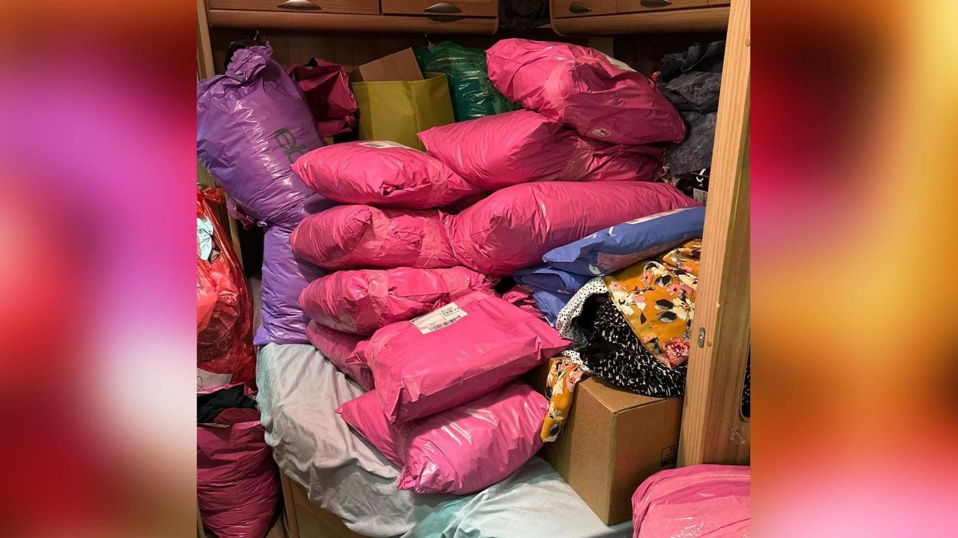 Llun sawl parsel pinc ar ben gwely yng ngharafán Rachel