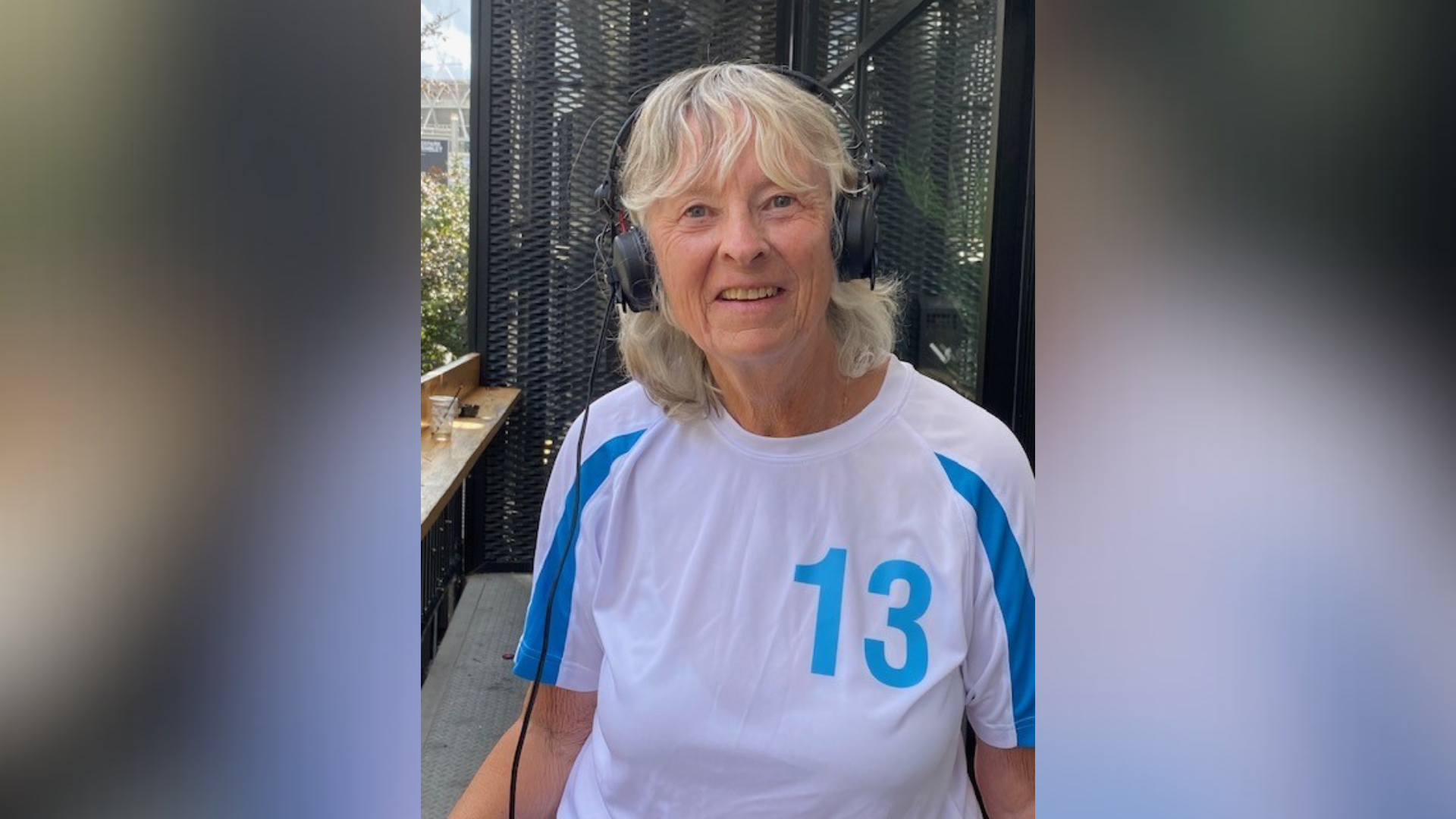 A woman wearing a blue and white shirt and black headphones.