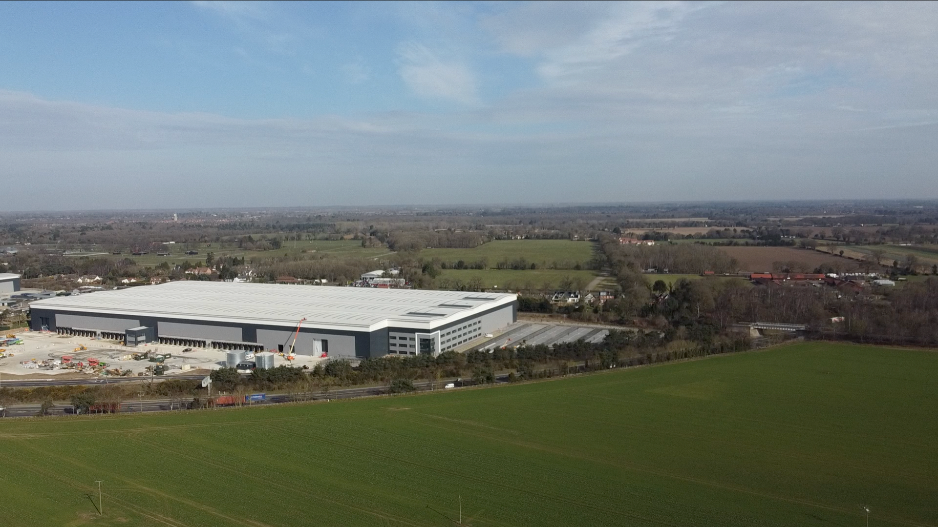 An aerial shot showing the warehouse next to large green field and in front of homes in Felixstowe Road 