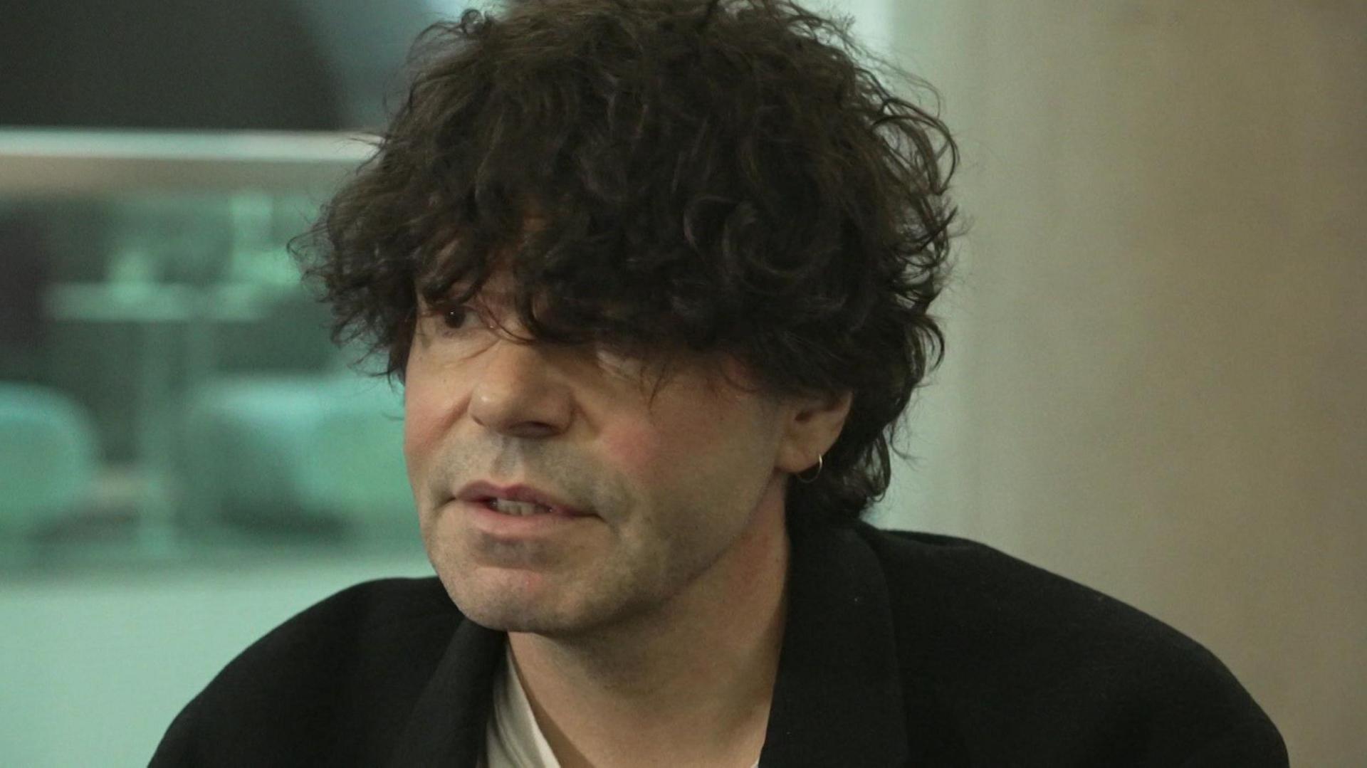 Tim Burgess, with his trademark floppy black hair, speaks to the BBC in a Salford office.