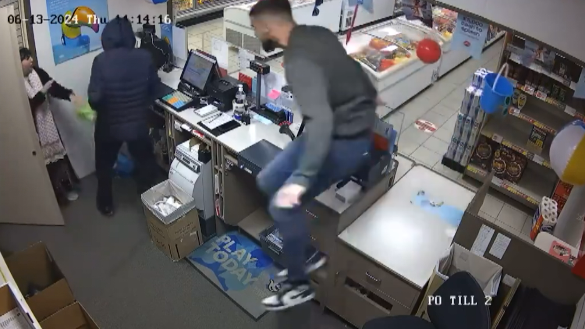 CCTV image of staff grabbing would-be robber Robert Daneskin behind the counter. One man is behind Daneskin and has his arms wrapped around him. Daneskin is wearing a balaclava and blue coat, while holding an imitation gun and a bag in his hand 