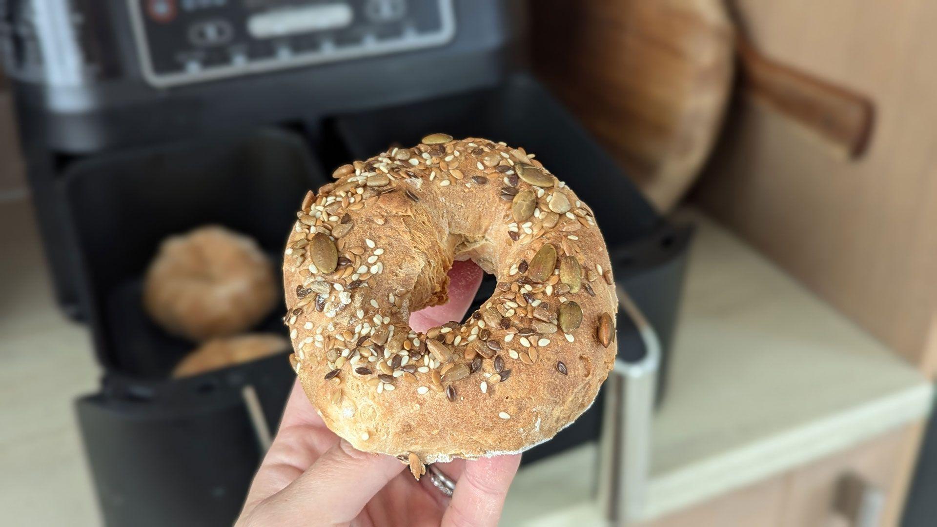 Helen holding one of the bagels with the air fryer in the background