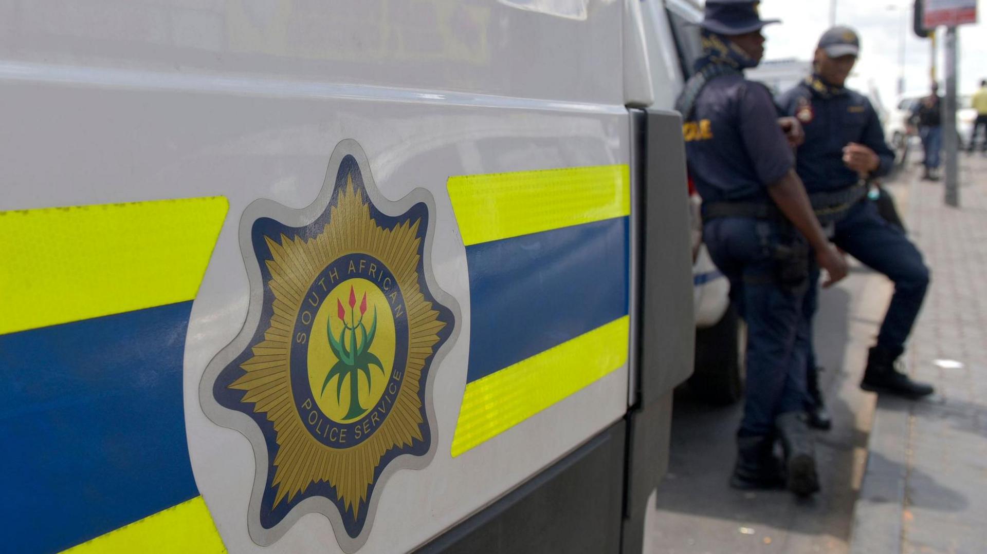 A South African police-branded vehicle is seen next to officers