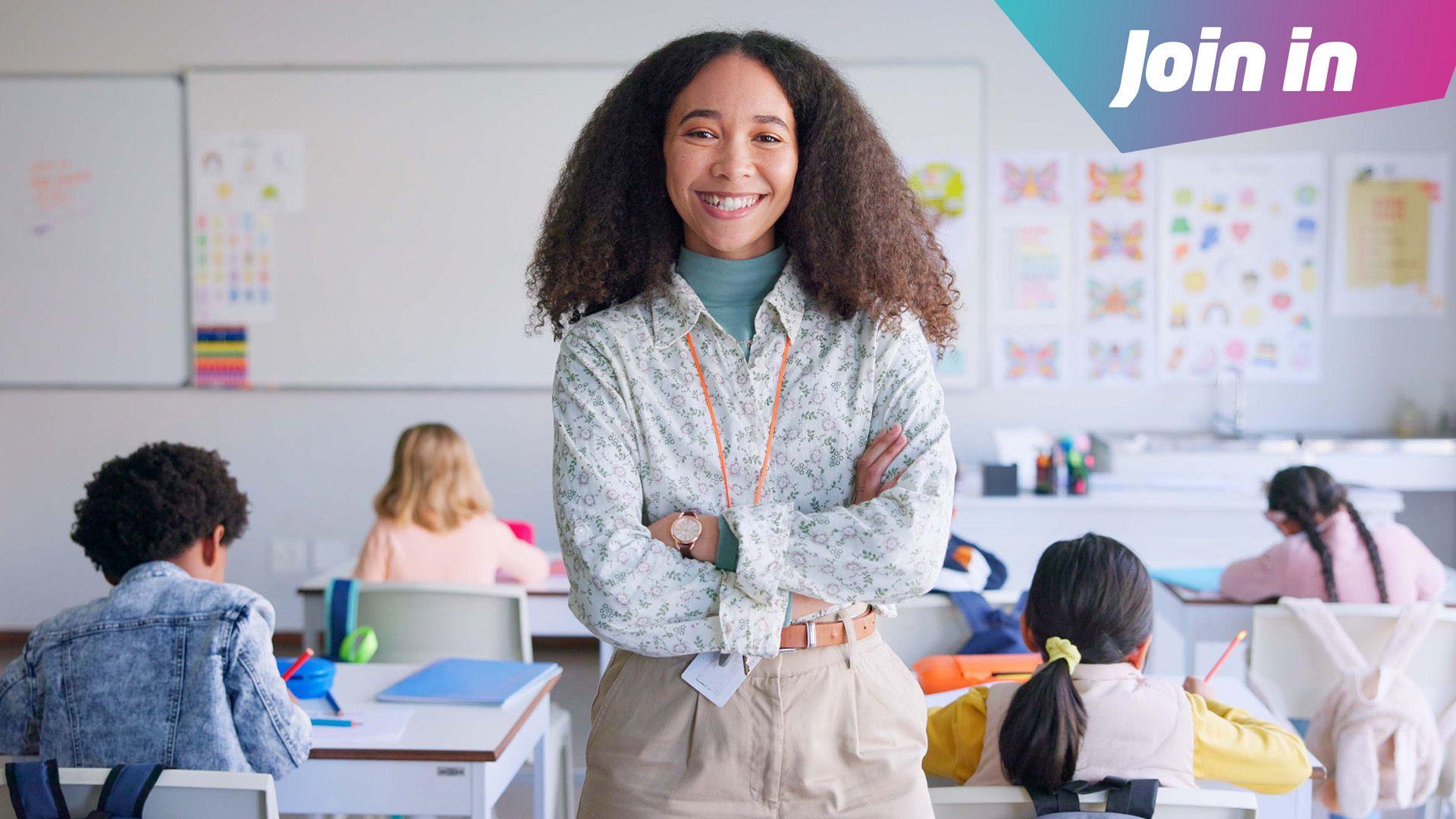 Teacher stands in a classroom surrounded by working children 