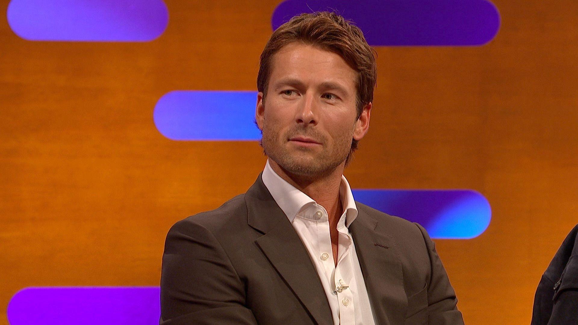 Glen Powell on the Graham Norton show wearing a brown suit and a white shirt