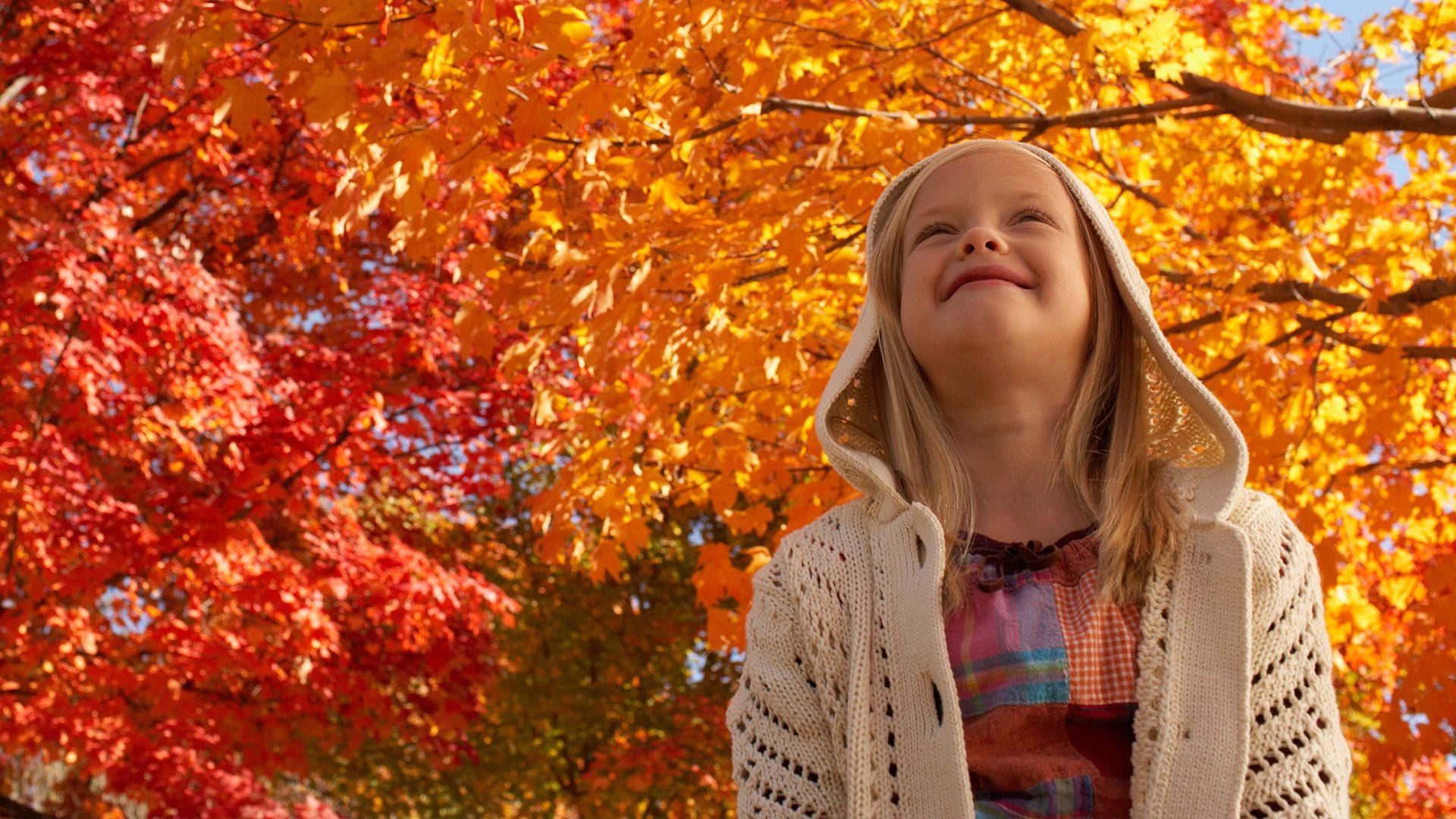 Girl surrounded by trees with red and orange leaves