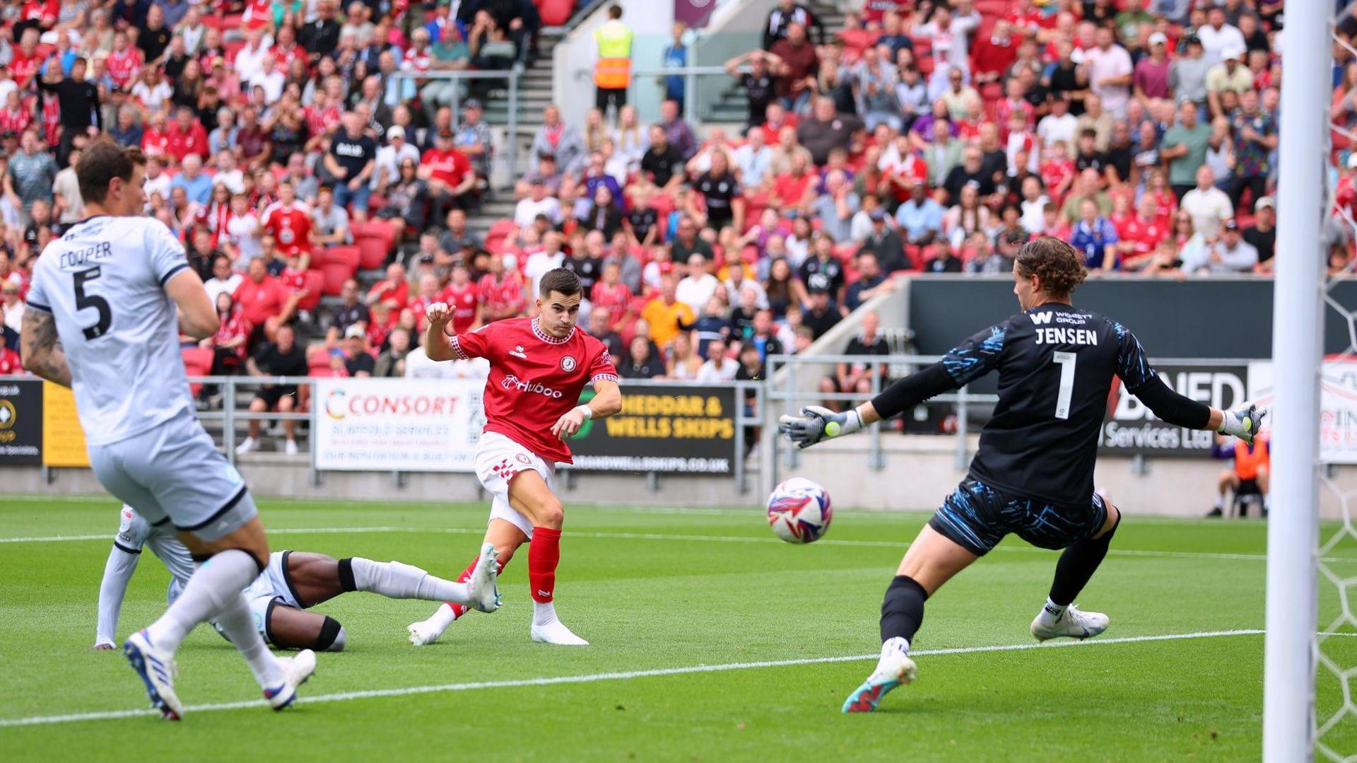 Bristol City player Anis Mehmeti scores his team's first goal against Millwall at Ashton Gate on Saturday. He is shooting with his right foot and the ball is visible as it flies past the Millwall goalkeeper