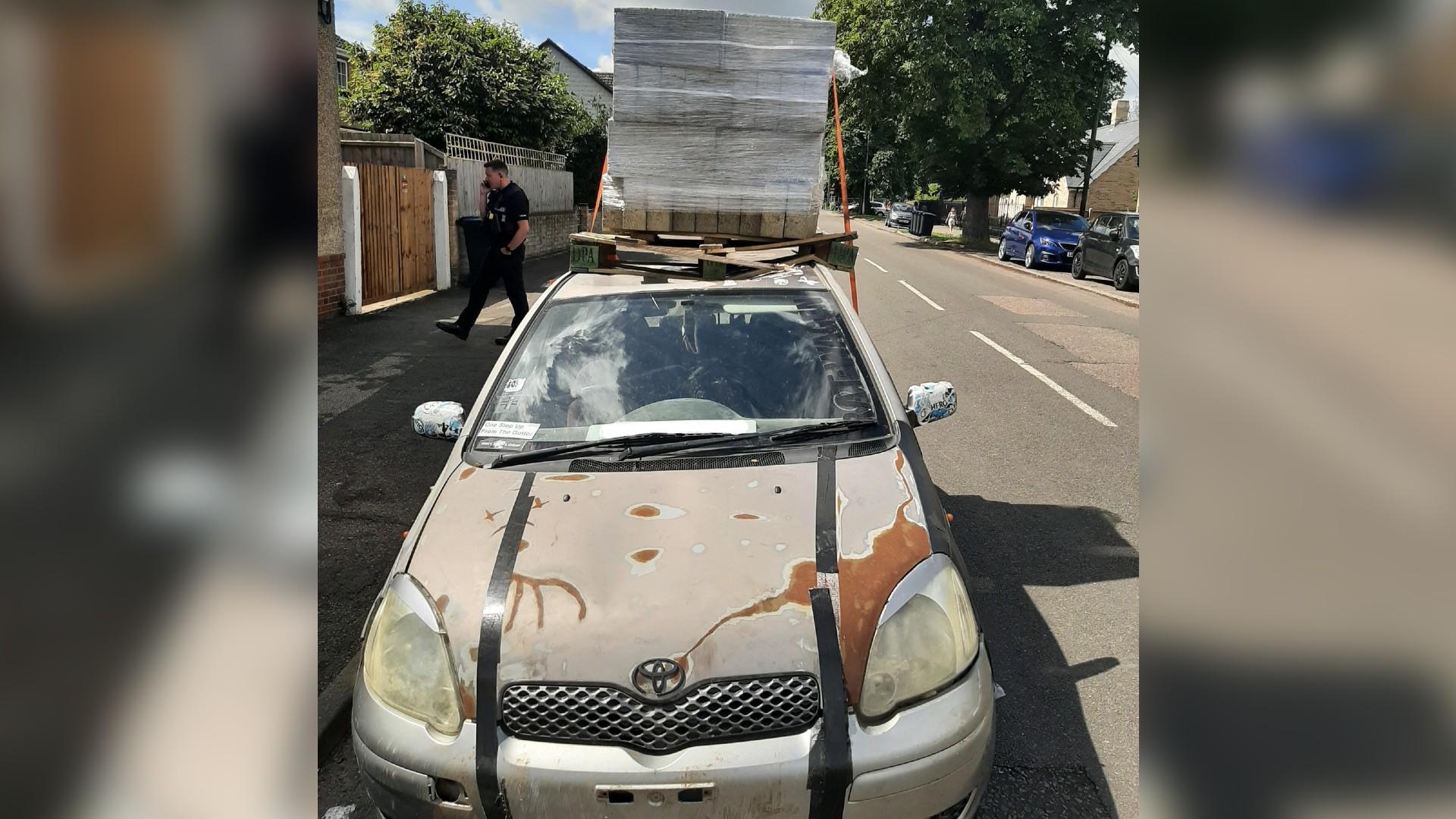 Car with heavy load of bricks on roof