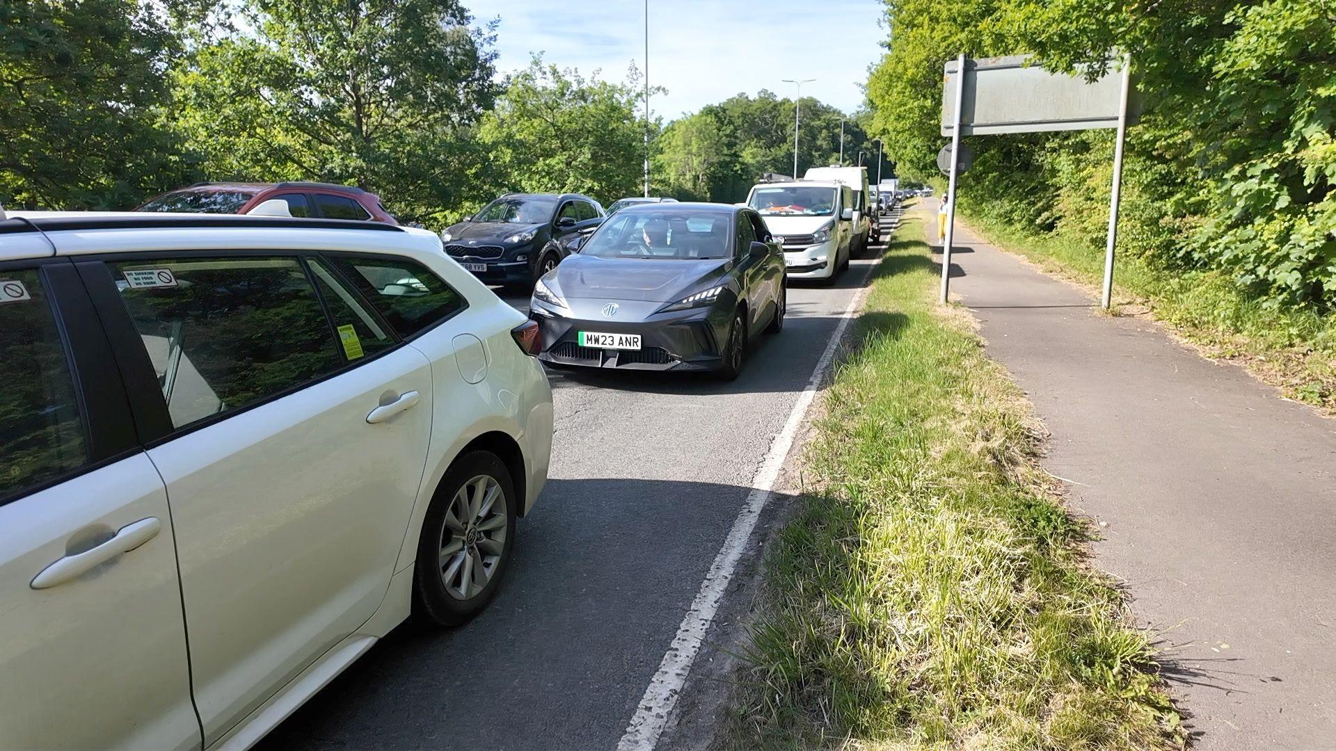 Two lanes of traffic are queued back up a hill with some drivers reporting delays of up to two hours.