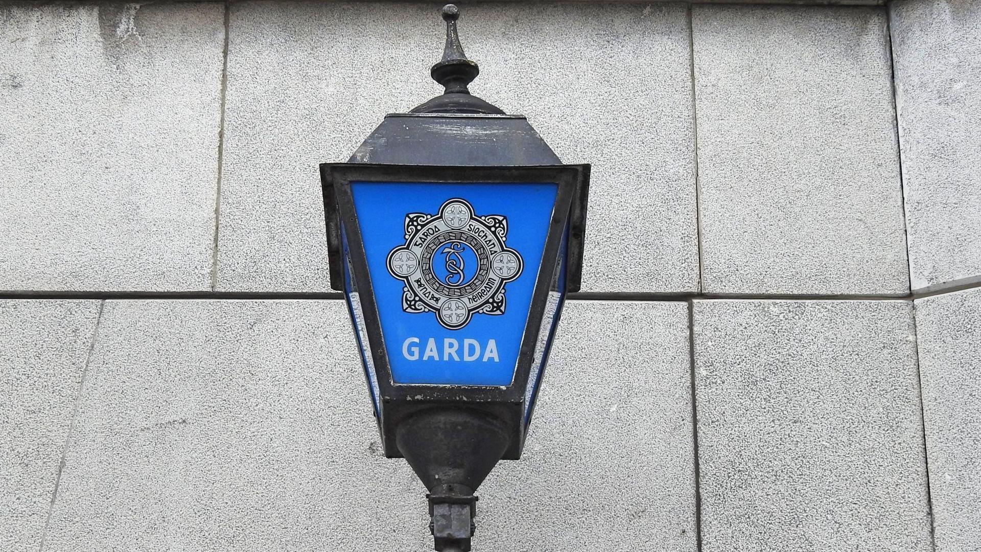 A blue and black Garda light sits on a grey stone wall