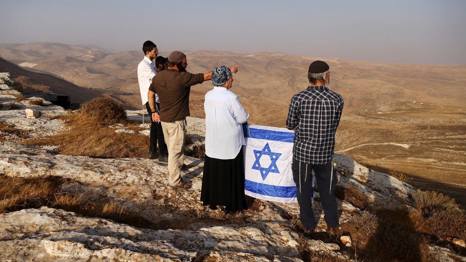 Daniella Weiss, a veteran settler leader, holds an Israeli flag during a scouting mission to find new hilltops to settle near the Israeli settlement of Kokhav Hashahar, in the occupied West Bank (6 November 2022)