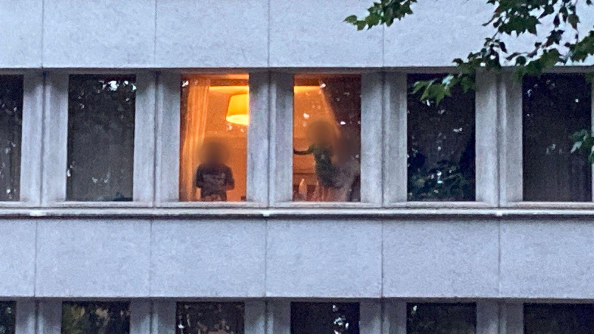 People, including children, looking out of a hotel room with a light on