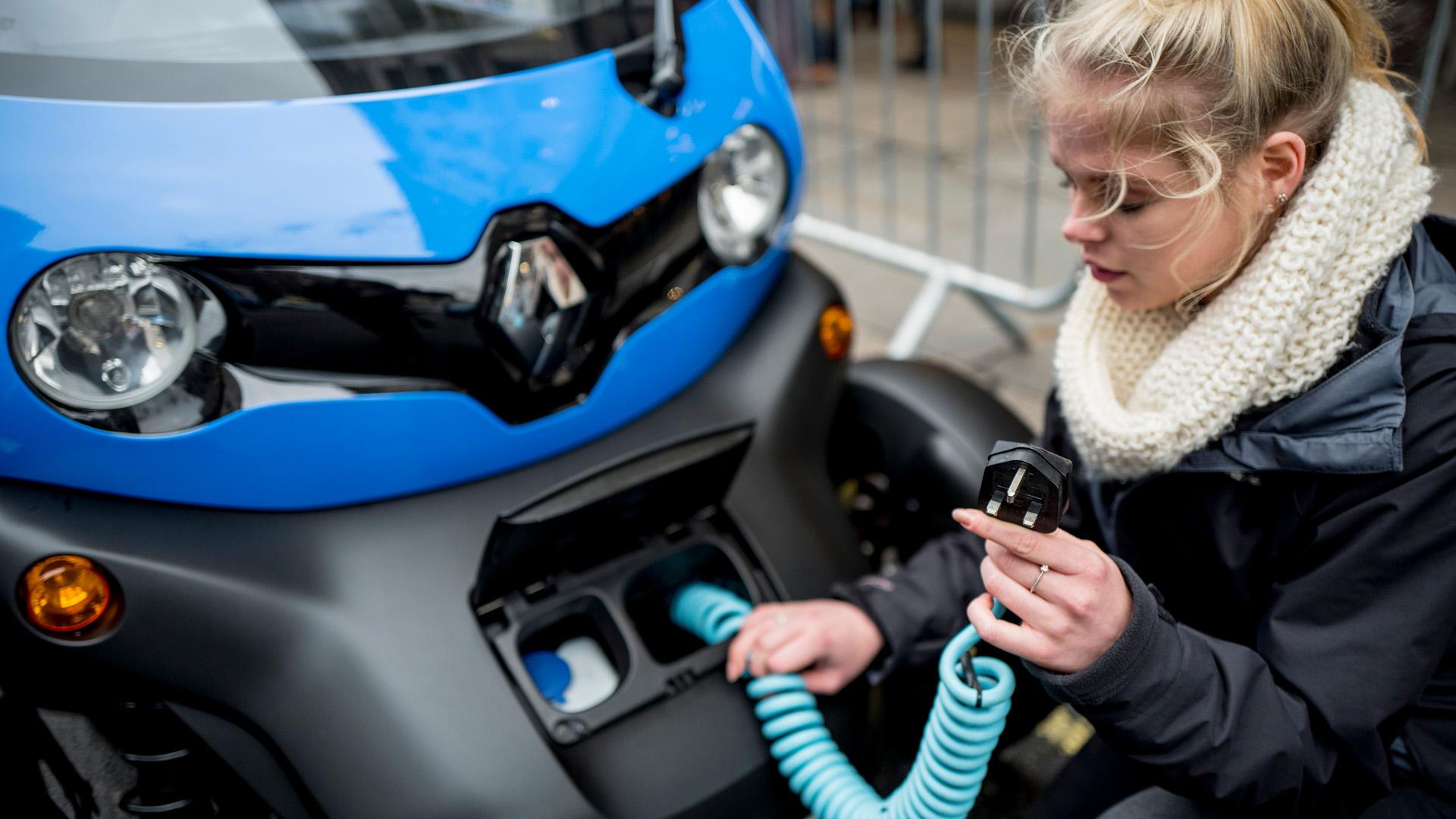 A woman charges an electric vehicle