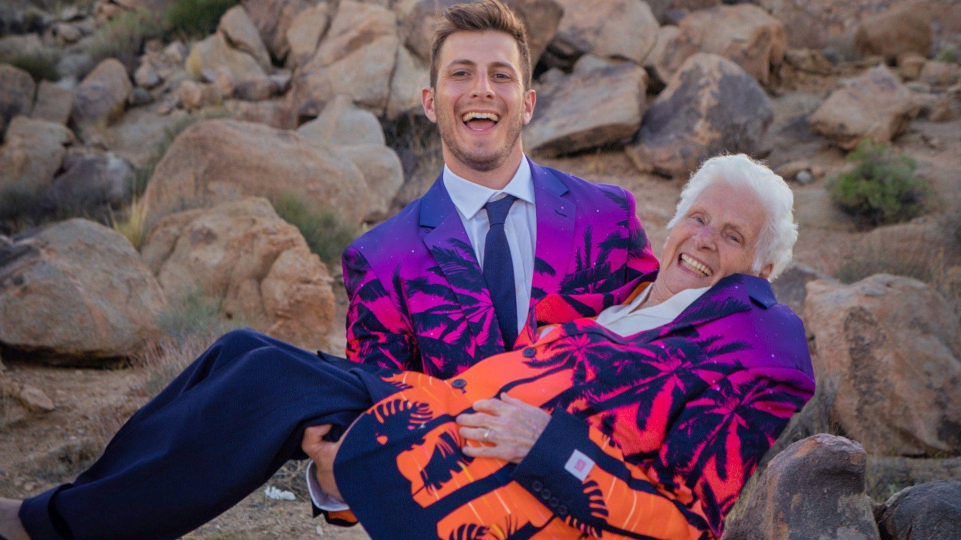 Young man in colourful blazer holds an older woman in the same blazer