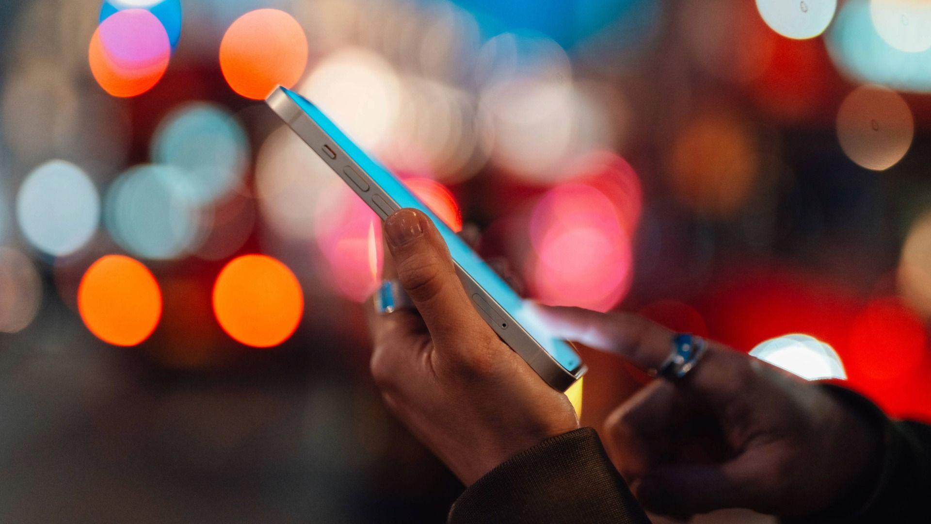 Llun o ddwylo'n defnyddio ffôn symudol