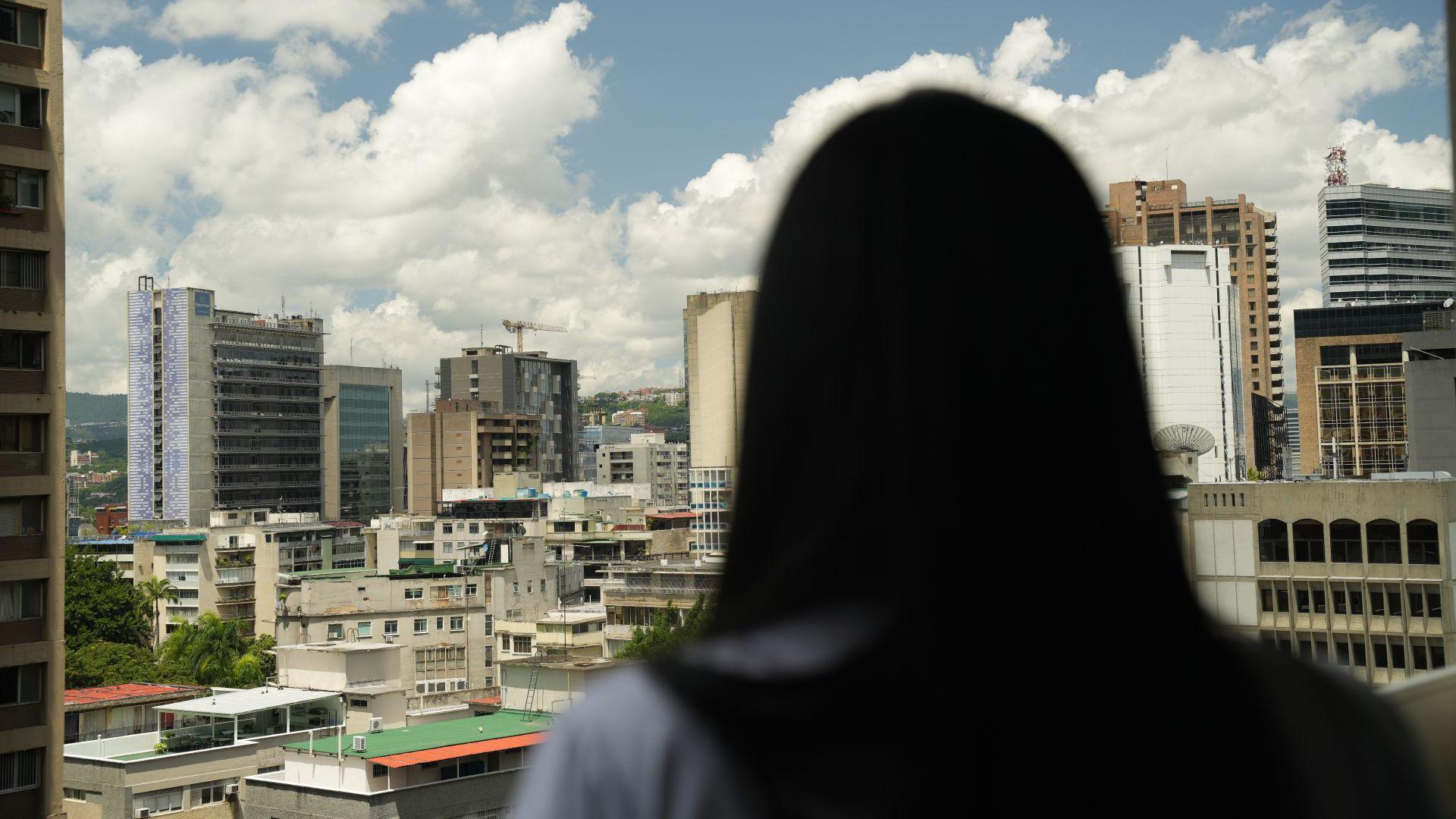 An unidentified woman stands in front of the Caracas skyline