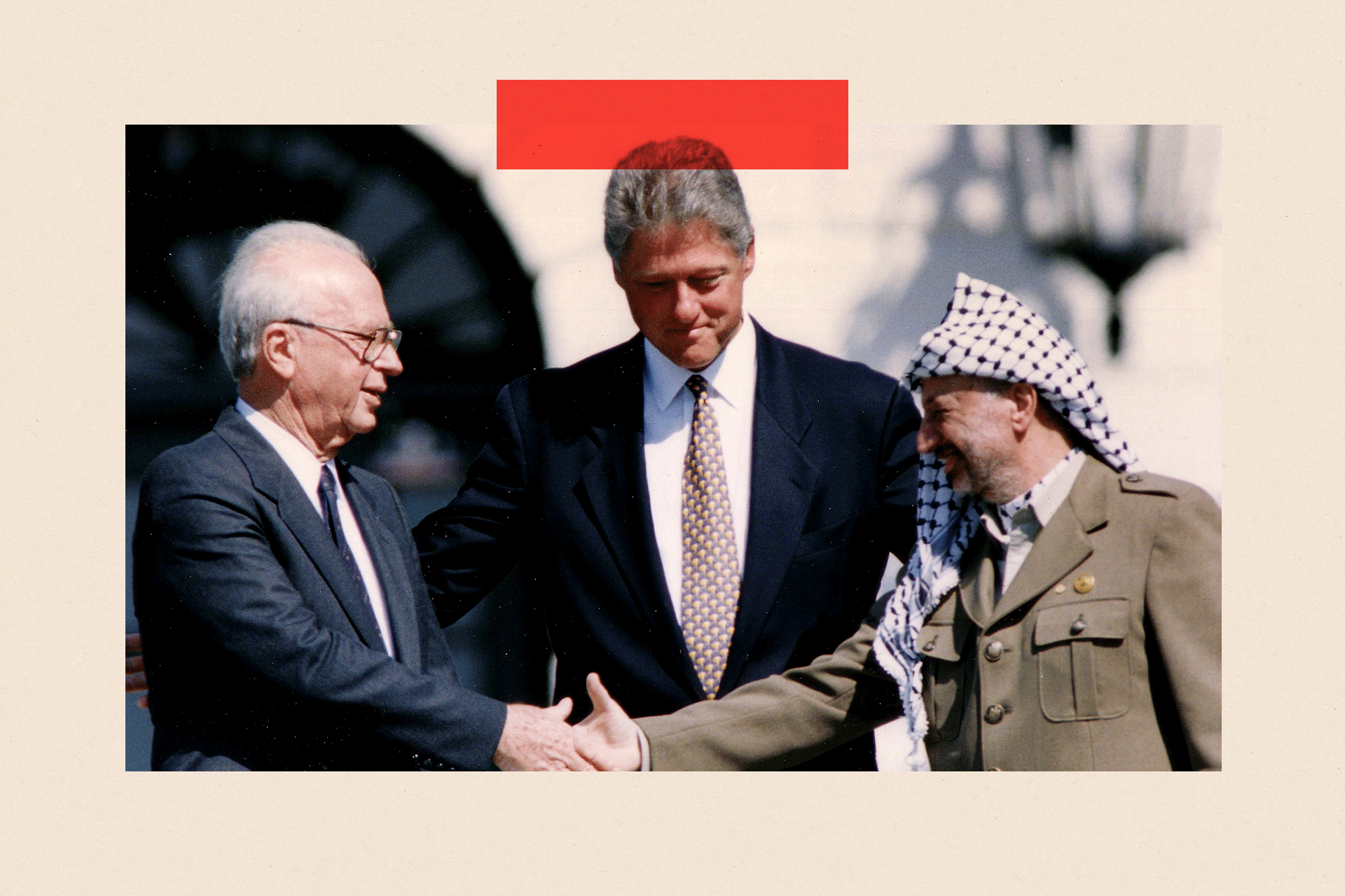 PLO Chairman Yasser Arafat (R) shakes hands with Israeli Prime Minister Yitzhak Rabin (L), as U.S. President Bill Clinton stands between them, after the signing of the Israeli-PLO peace accord