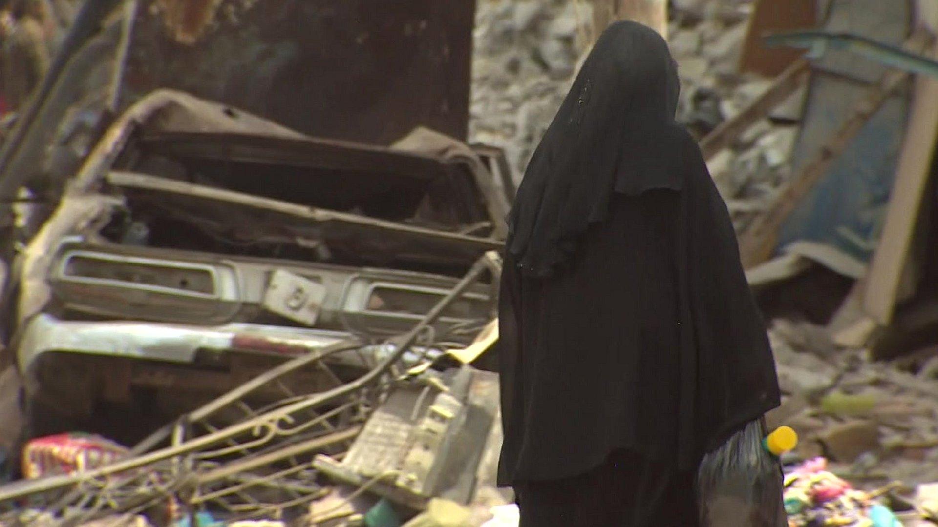 Woman walks among rubble in Aden