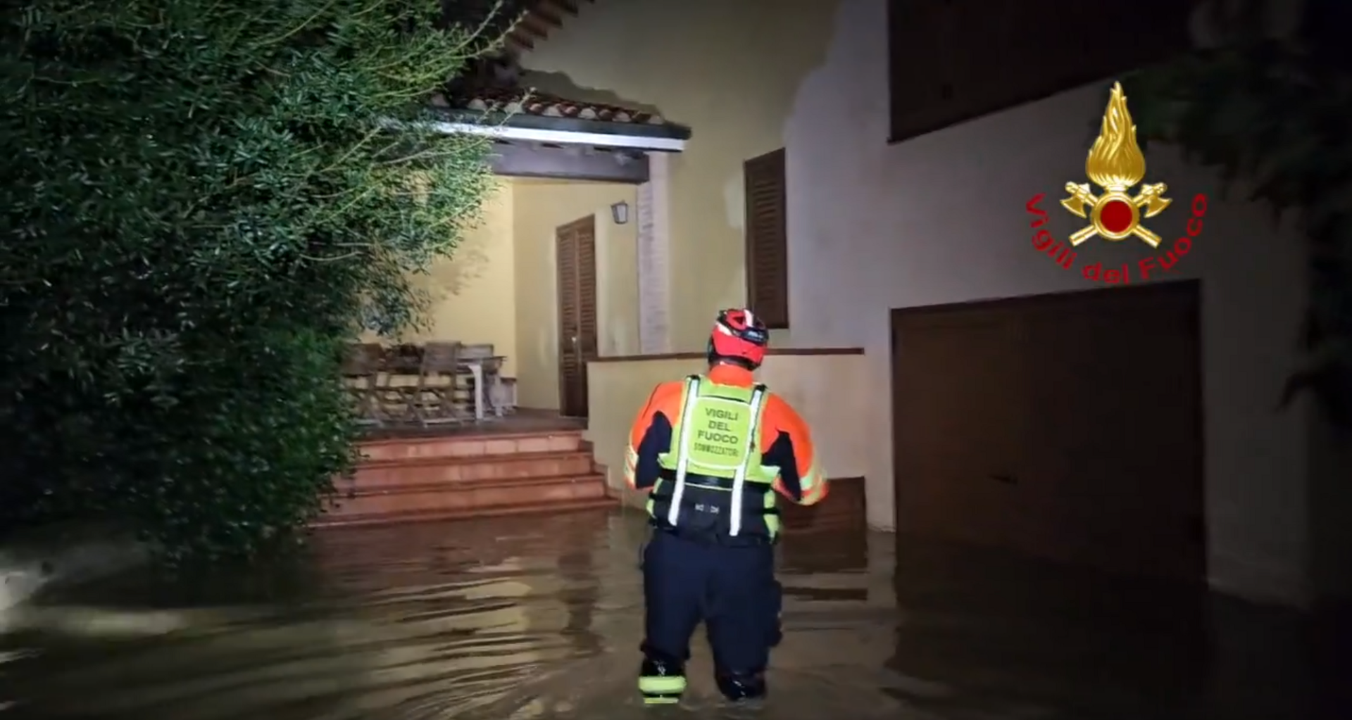 A firefighter wading into a house amid floodwater