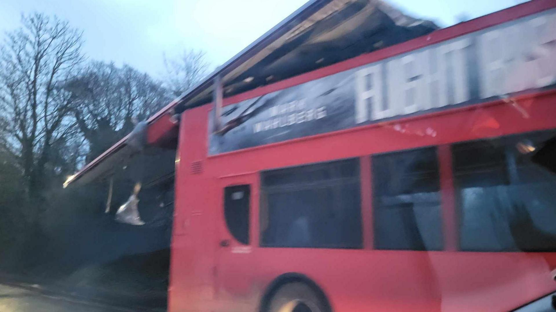 A blurry photos of a red double decker bus with its roof hanging off the back of it in a road - with an advertisement for the film Flight Risk